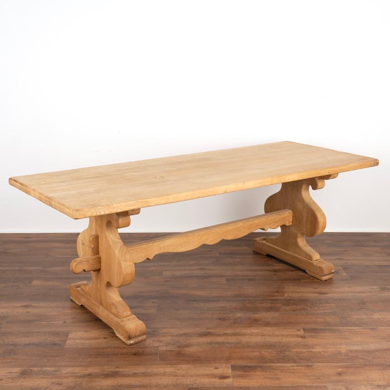 This French country farm table is impressive at almost 7'long. It has been given new life with a bleached oak finish, adding a fresh look to this timeless classic. Note the thickness of the solid oak top and heavy trestle base. Unique to this table