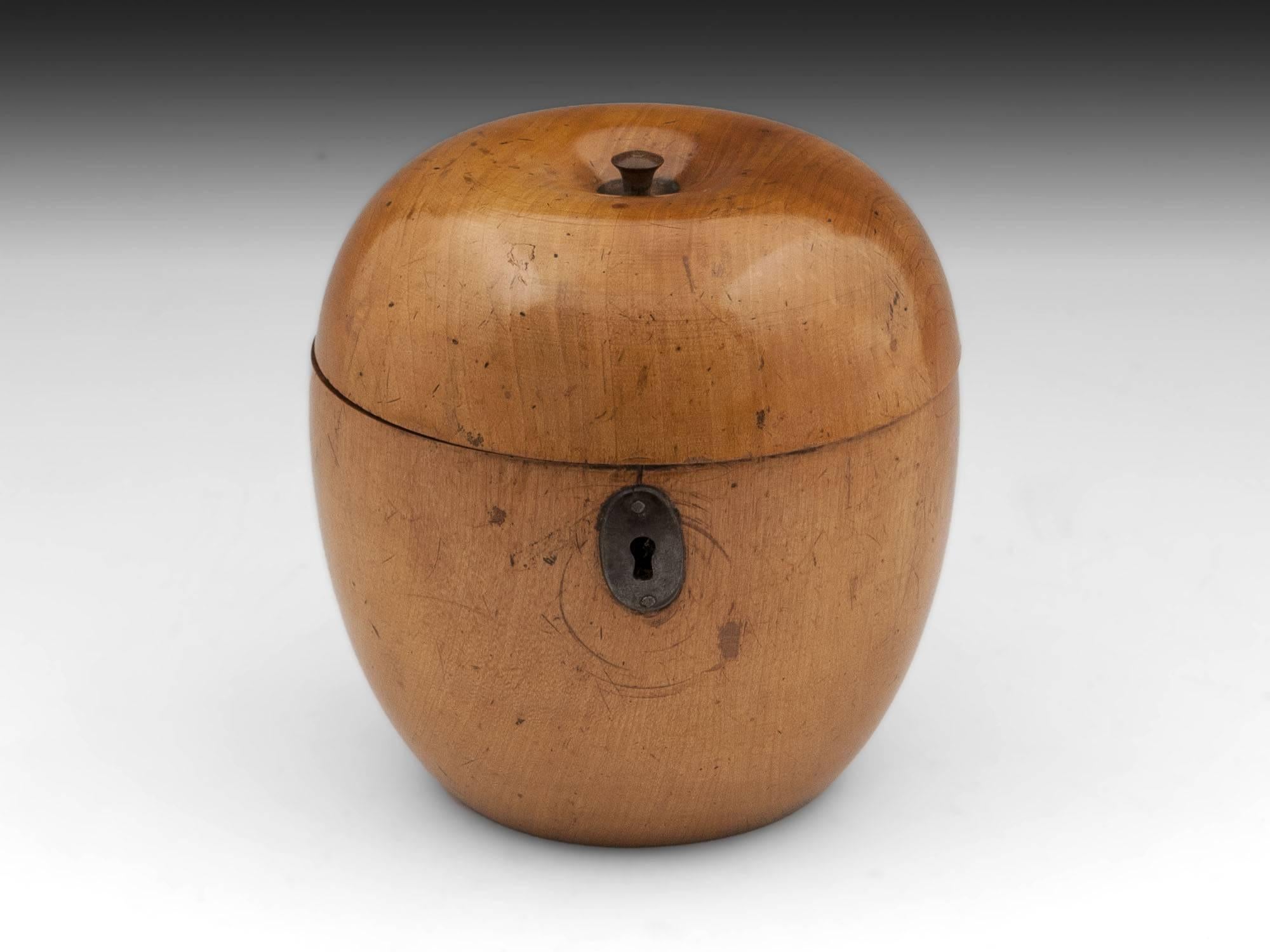 Antique apple tea caddy with great blonde color and patination, has button stalk and oval cut steel escutcheon.
This fabulous treen apple caddy interior still has traces of its original tin foil lining, comes with a fully working lock and tasselled