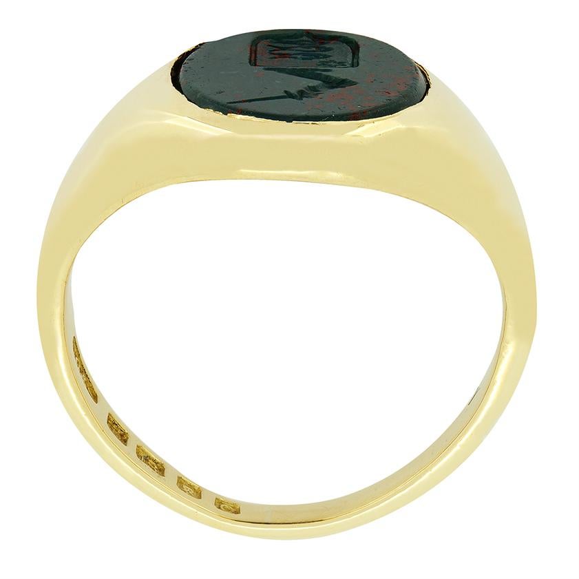 With hallmarks dating back to 1938 this charming Signet ring features a rich green blood stone bearing an engraved crest of a sheild topped by a sword in hand. Crafted in 18 carat yellow gold this classically designed signet ring weighs 6.1