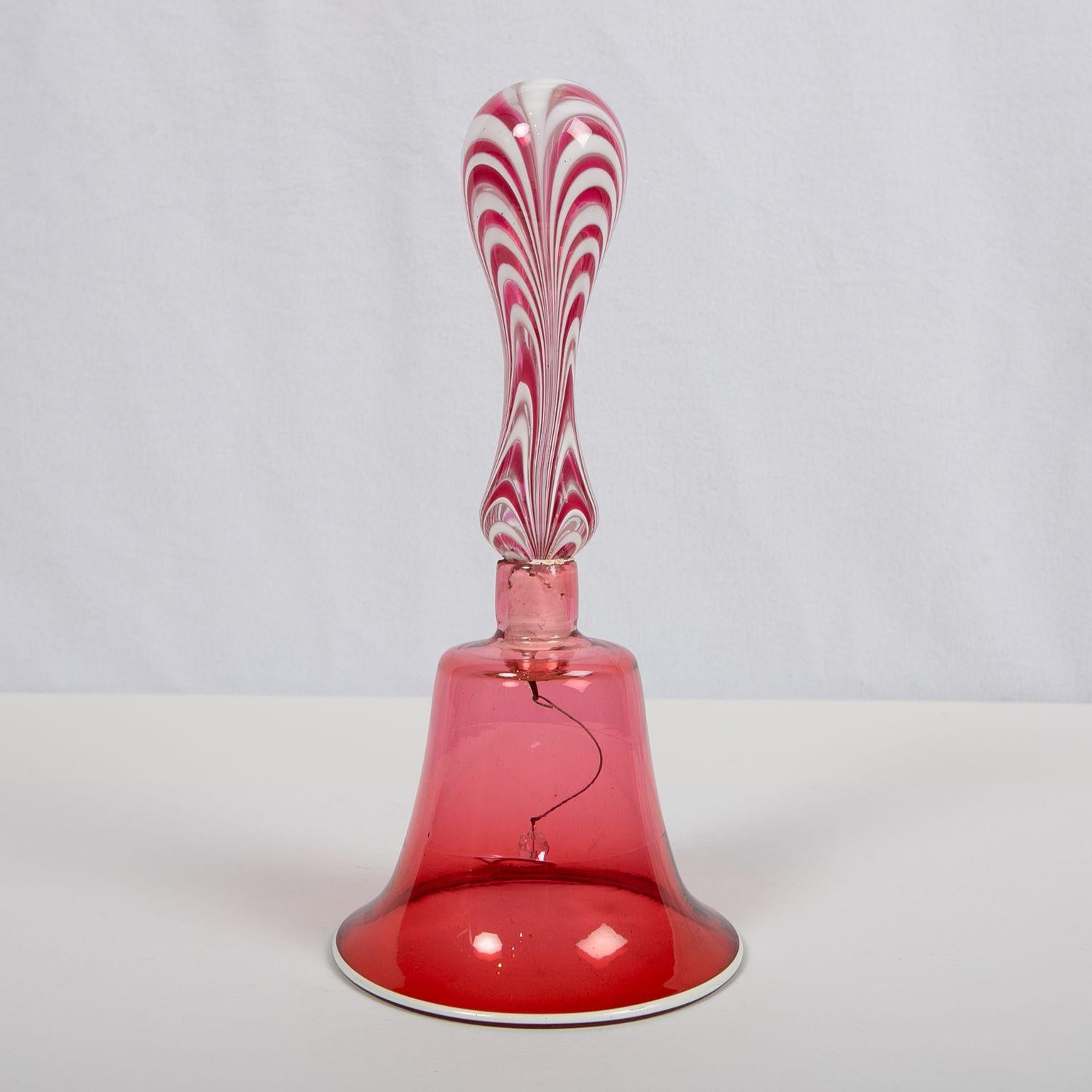 This handmade blown glass wedding bell was made in England at the Nailsea Glassworks, circa 1840. The shape of the bell and handle is elegant. The deep red color of the bell is exquisite. The handle looks like peppermint with swirled red and white