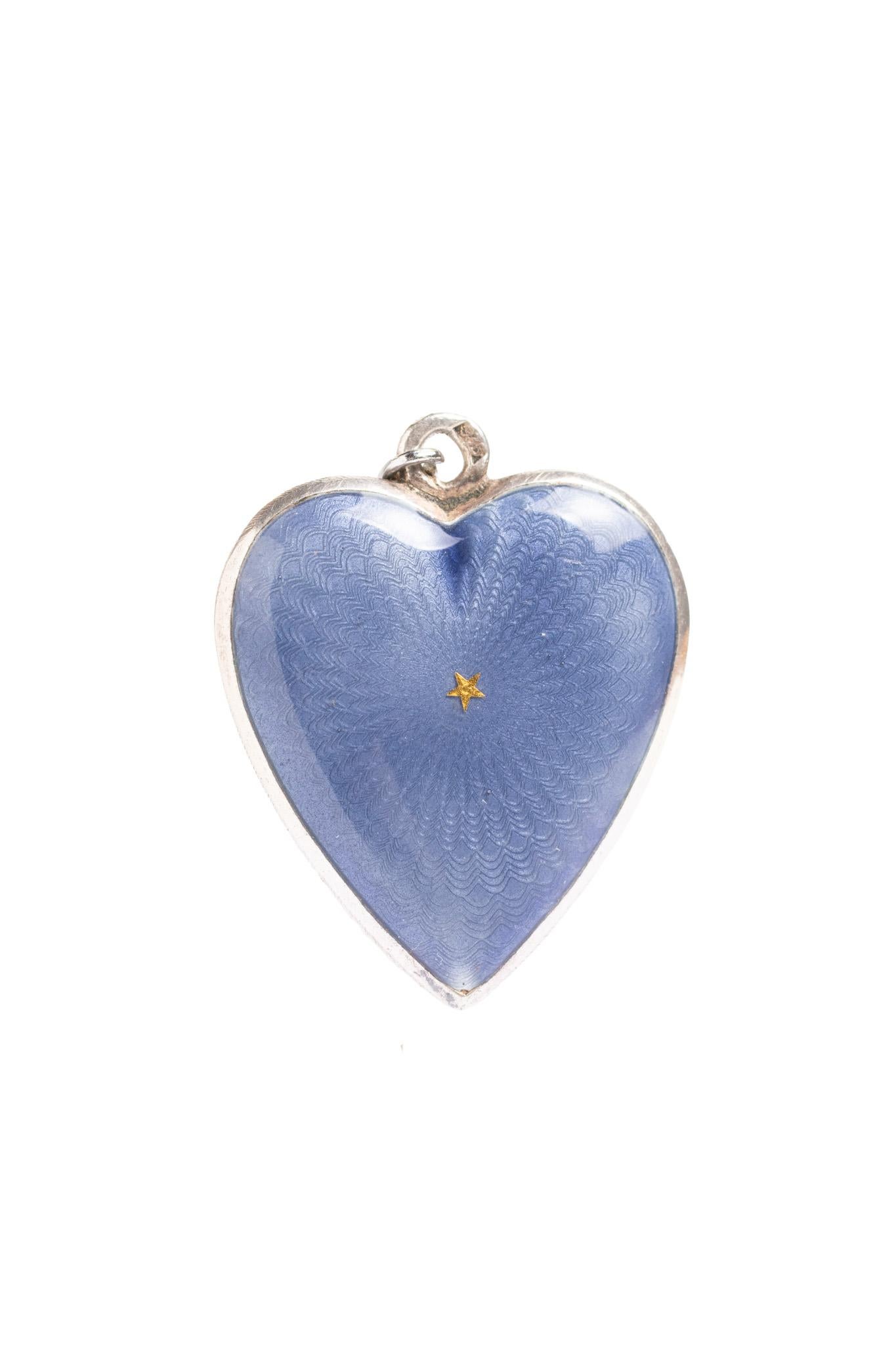 A striking and rare antique heart-shaped pendant necklace beautifully decorated with vibrant deep blue guilloché enamel and a single gold star at the center. This pendant is a fine example of early 20th-century European craftsmanship, likely from
