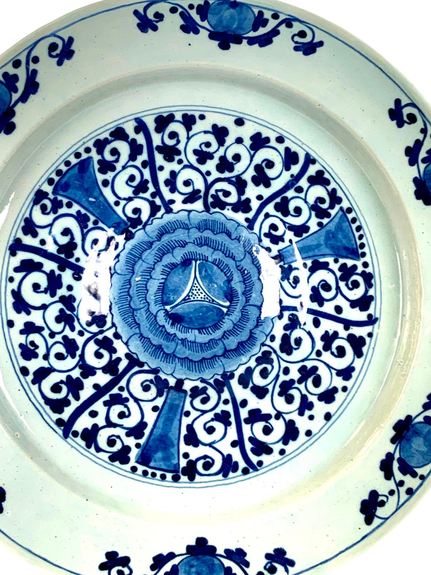 Cet élégant chargeur bleu et blanc de Delft a été peint à la main aux Pays-Bas vers 1770.
Le centre est orné d'un délicat enroulement de vignes tourbillonnant autour d'une belle fleur.
Deux tons de bleu sont utilisés pour faire ressortir la grande