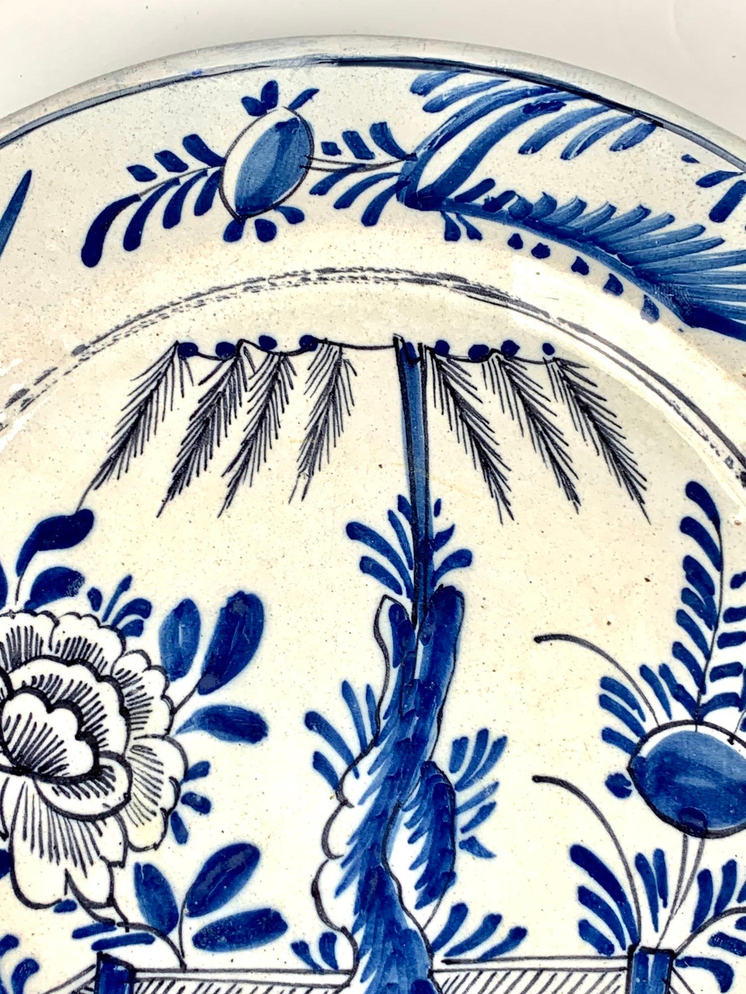 Hand painted circa 1780, this eye-catching blue and white Delft charger is hand painted in shades of cobalt blue with black accents.                              
The artist has captured a vibrant garden scene transporting the viewer to a world of