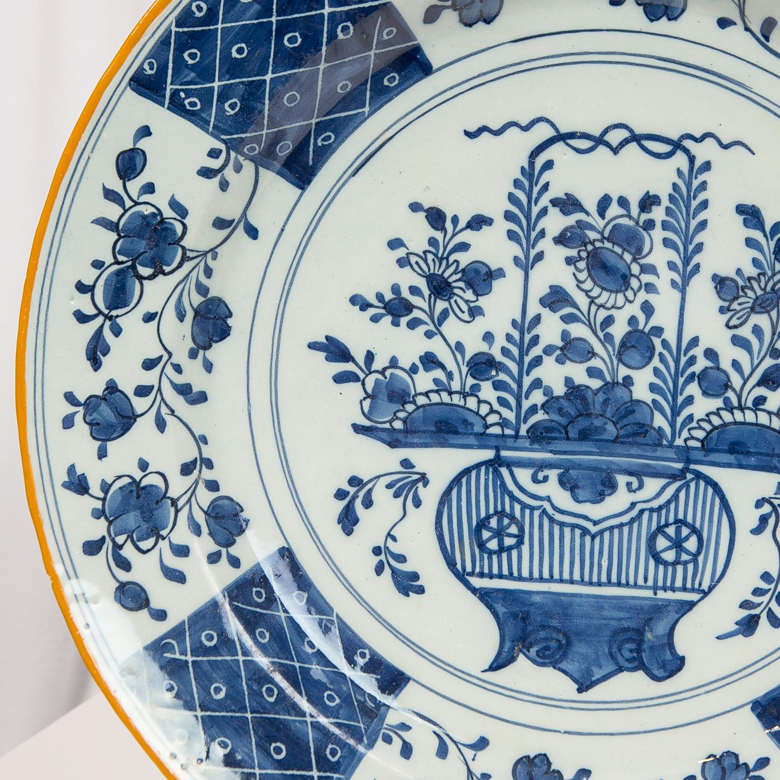 We are pleased to offer this pair of Dutch Delft blue and white chargers decorated in the center with an image of a delicate vase filled with chrysanthemums and peonies. 
The design in the center of the charger is derived from Chinese decoration,