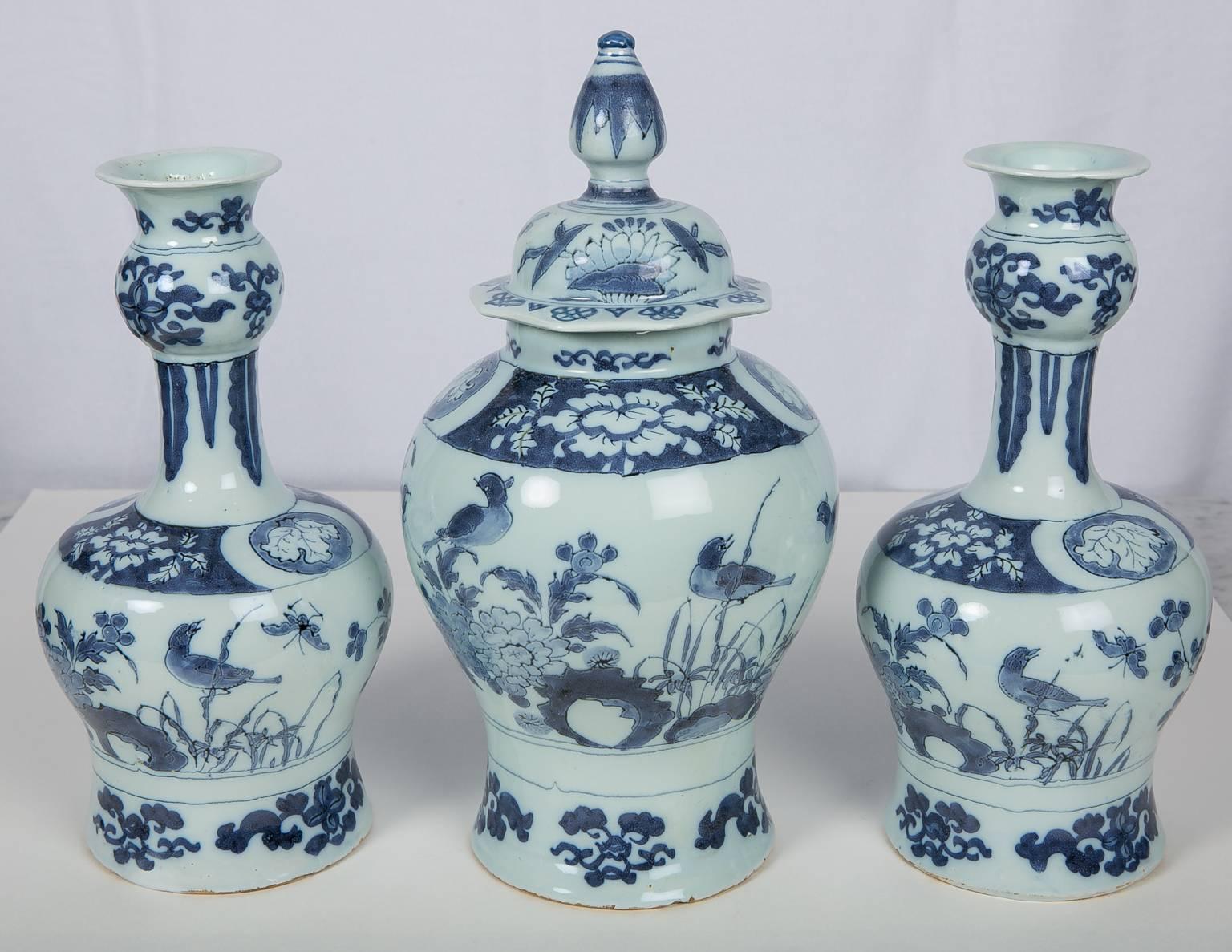 An antique Dutch Delft garniture of three vases: one covered and two gourd shaped.
The soft palette of the songbirds and their surroundings set against the palest blue ground makes this garniture particularly beautiful. The songbirds are perched
