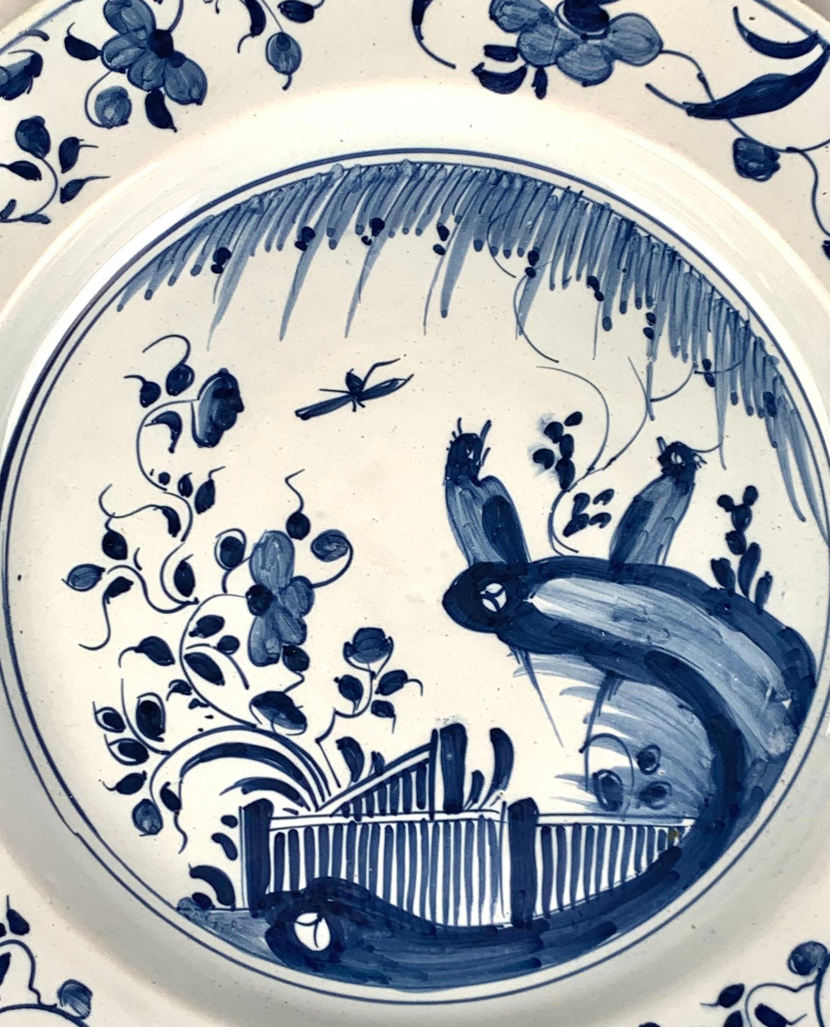 Produced in Bristol, England, circa 1760, this handpainted blue and white Delft charger is a visual delight.
The center of the charger features a flower garden with songbirds seated on rockwork.
The songbirds are perched beneath a willow tree while