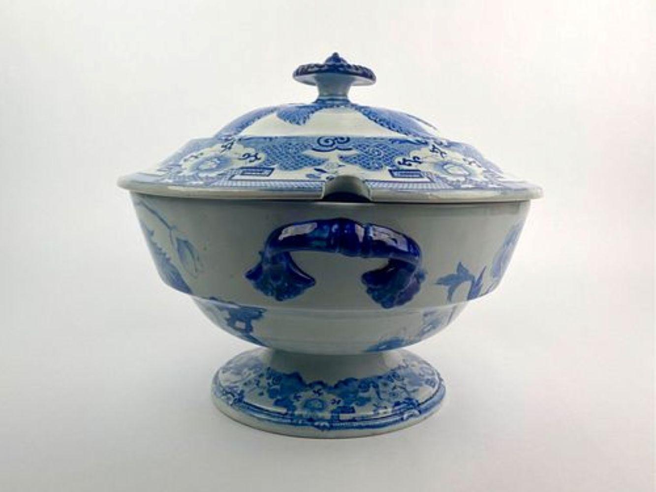 Grande soupière couverte en pierre de fer sur une base à pieds, présentant une décoration par transfert typique de l'époque, d'un beau bleu cobalt profond sur fond blanc. L'objet est décoré de motifs floraux et d'oiseaux et doté d'un couvercle bombé