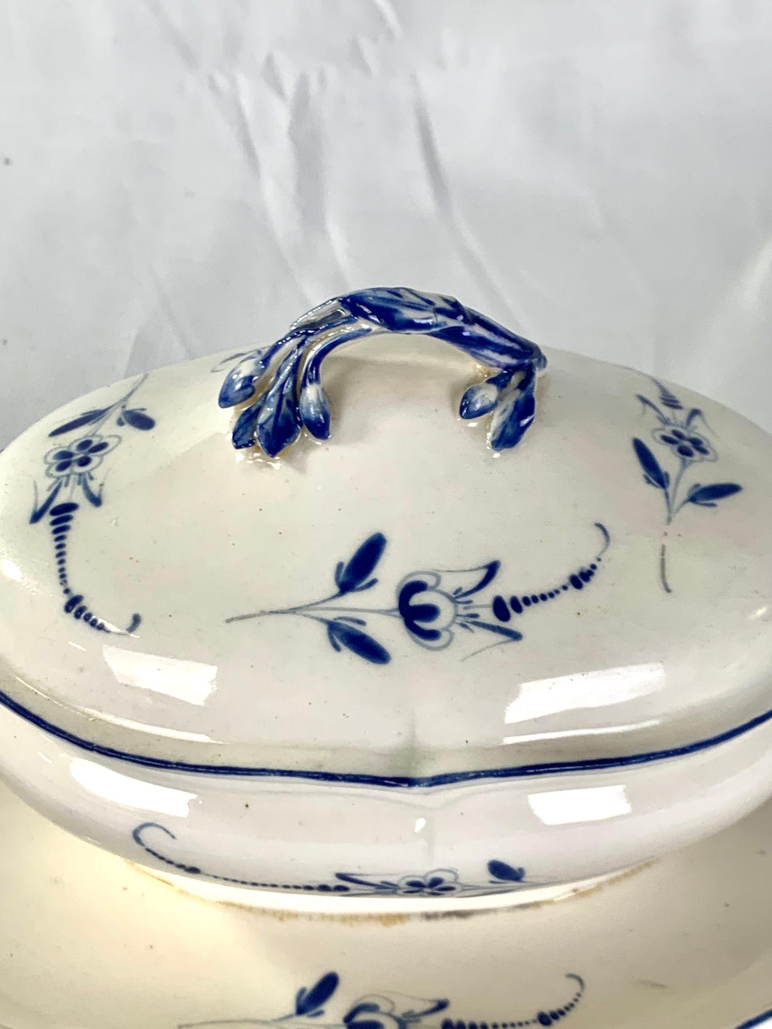 Questa deliziosa zuppiera in porcellana bianca e blu del XVIII secolo è stata dipinta a mano nella fabbrica di porcellana di Mennecy, in Francia, intorno al 1750.
Rametti di fiori sciolti dipinti in blu cobalto decorano la zuppiera e il suo supporto