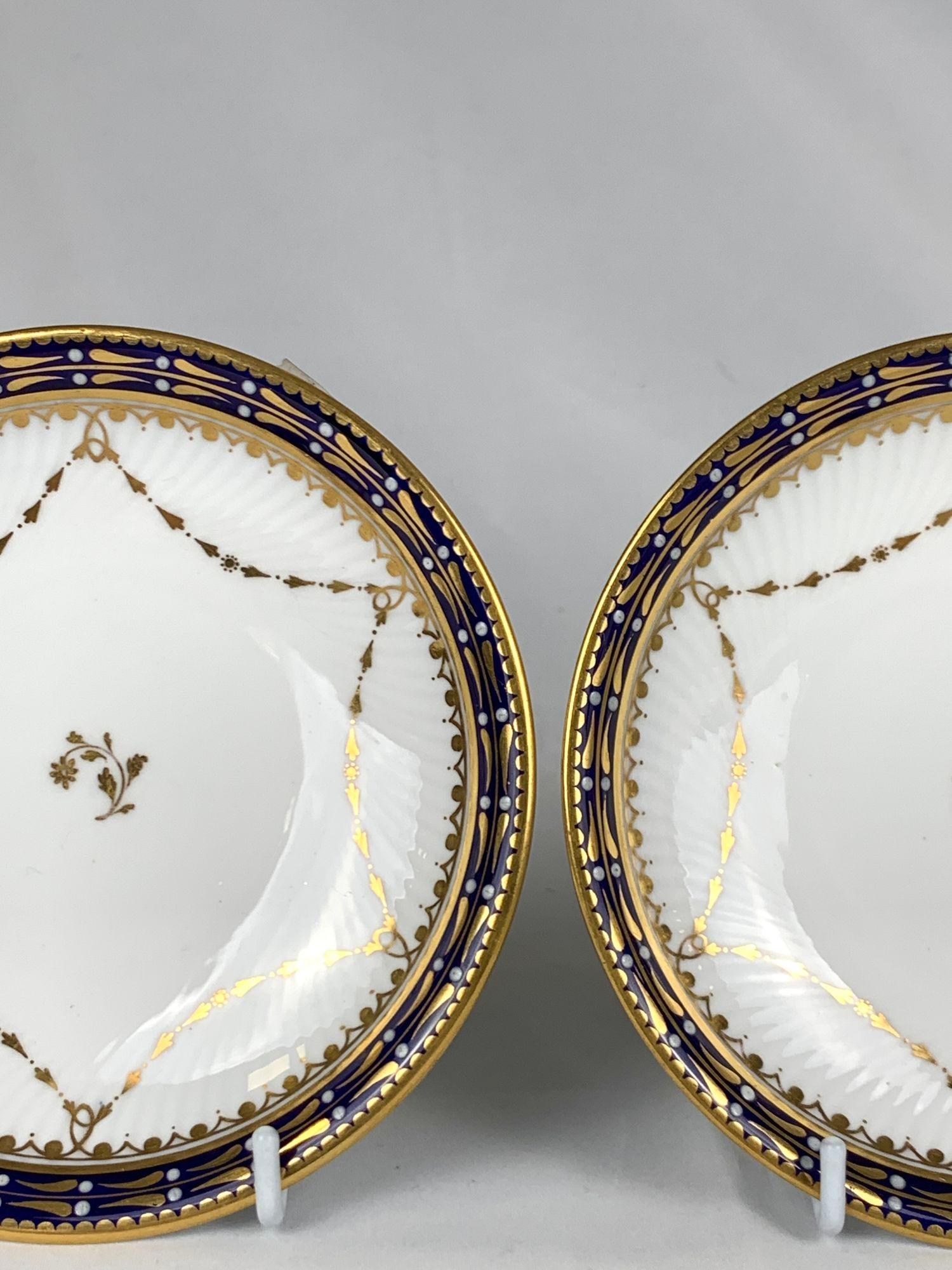 This elegant pair of English blue and white porcelain saucers was made by Copeland Spode for Mortocks Oxford Street in the late 19th century.
The white porcelain is decorated with swags of gold in a six-pointed pattern and is gently grooved.
The