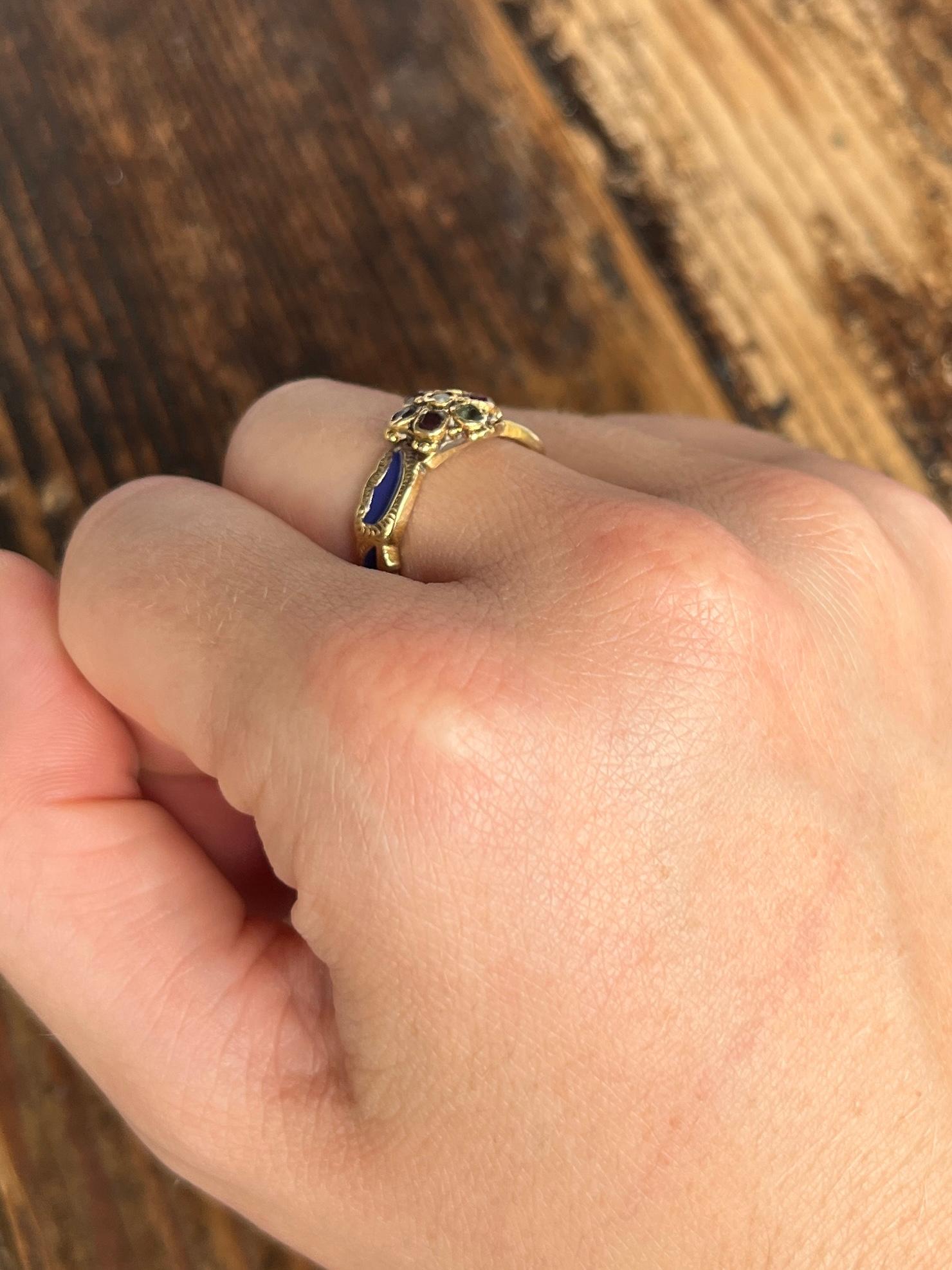 This antique band has dark blue enamel all the way around. The stones in the cluster at the front of the ring spells 