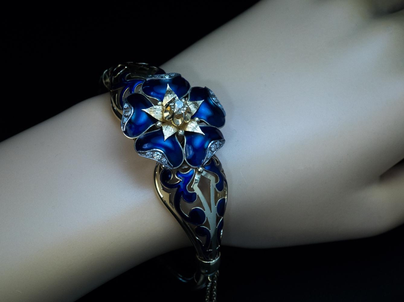 Circa 1890

Le bracelet ajouré à motif floral est réalisé en or jaune et en argent 14 carats. Il est orné d'émail brillant bleu cobalt, une couleur à la mode dans les bijoux de l'ère victorienne. La fleur est accentuée par des diamants.

Le poids