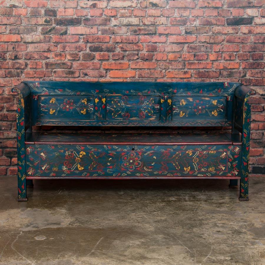 This delightful Hungarian Folk Art painted bench still retains the traditional elaborate floral motifs on a bright blue background. The bench seat lifts to reveal a large clean interior providing ample storage. Reflecting decades of use, the slight