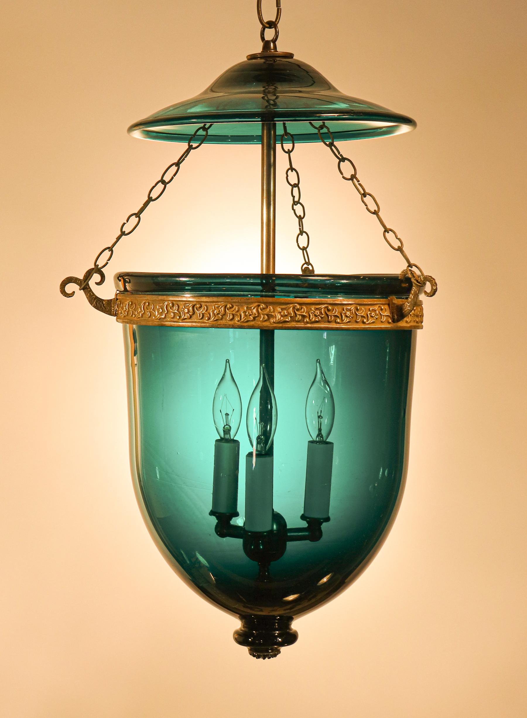 An exquisite dark teal hued bell jar lantern from England, circa 1870. This deep green-blue lantern has lovely form and is adorned with an authentic antique brass band that is embossed with a floral motif. The quality of the lantern is very good,