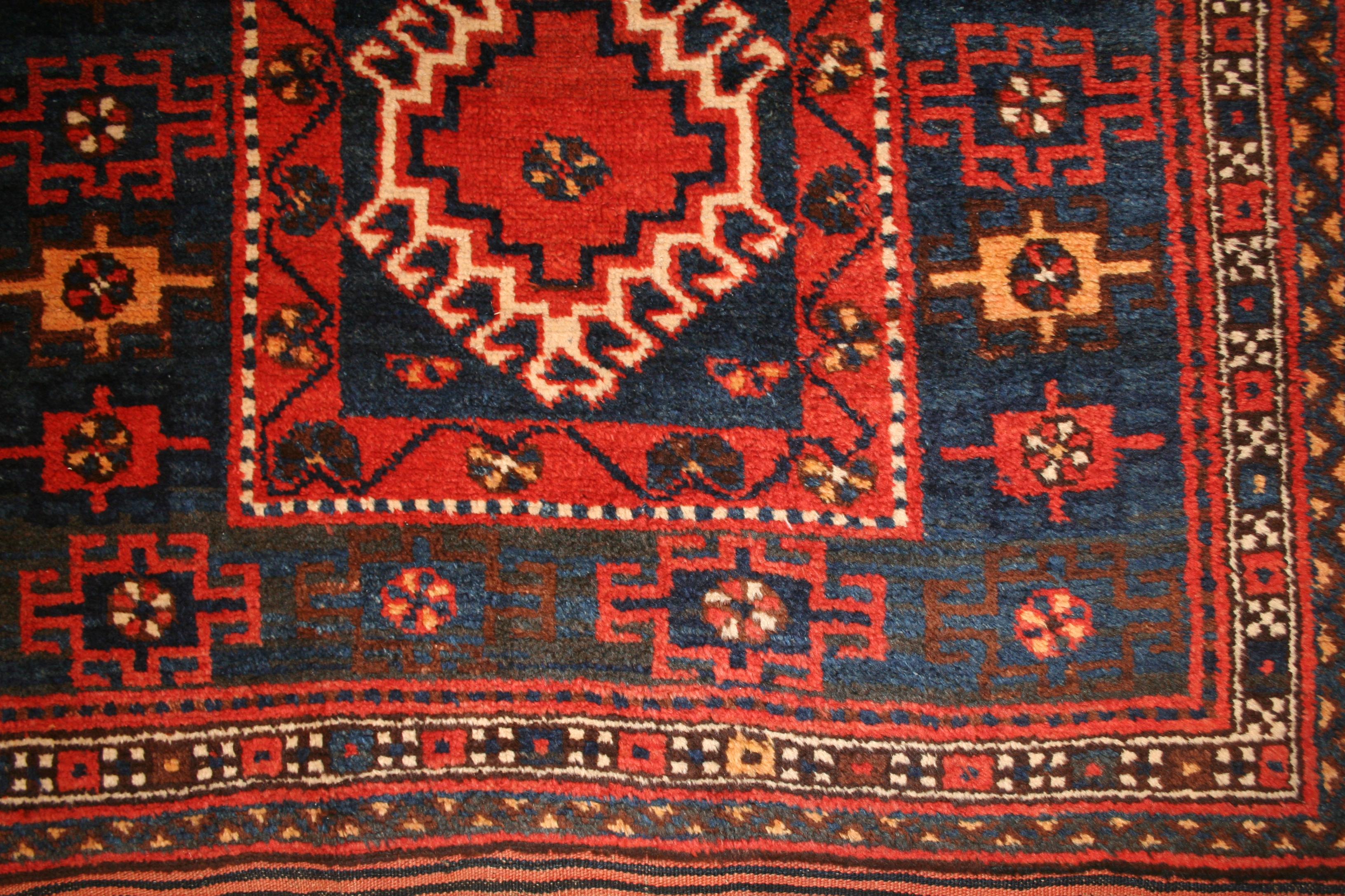 A beautiful antique Kurdish rug from the southern Caucasus, distinguished by its range of natural dyes, which include a rich indigo blue background, embellished by jewel-like tonalities of white, red, yellow and light blue. The central motif is