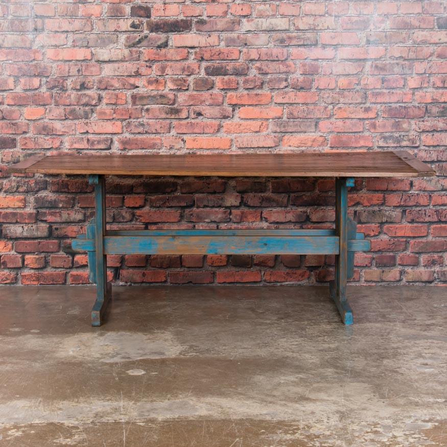 The appeal of this traditional Swedish farm table is the distressed blue painted trestle base that adds to the country charm. The pine top has been left natural, showing decades of use with a fantastic patina, and sealed with a wax finish. Please