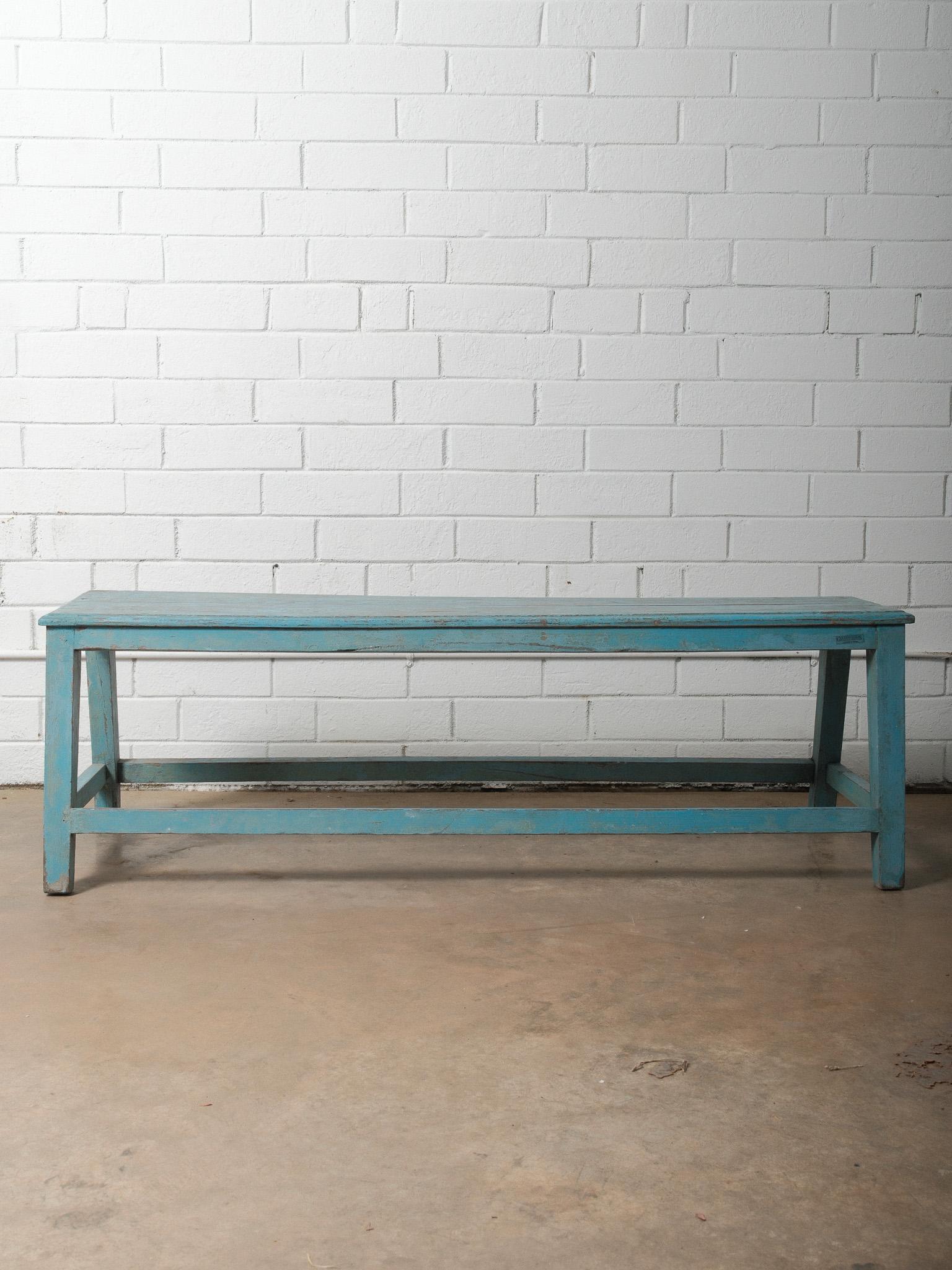 Un banc ancien en bois peint en bleu présente un caractère magnifiquement usé par le temps et une patine de surface authentique. Le banc présente un long plateau rectangulaire avec une peinture bleue légèrement usée, révélant un bois naturel chaud