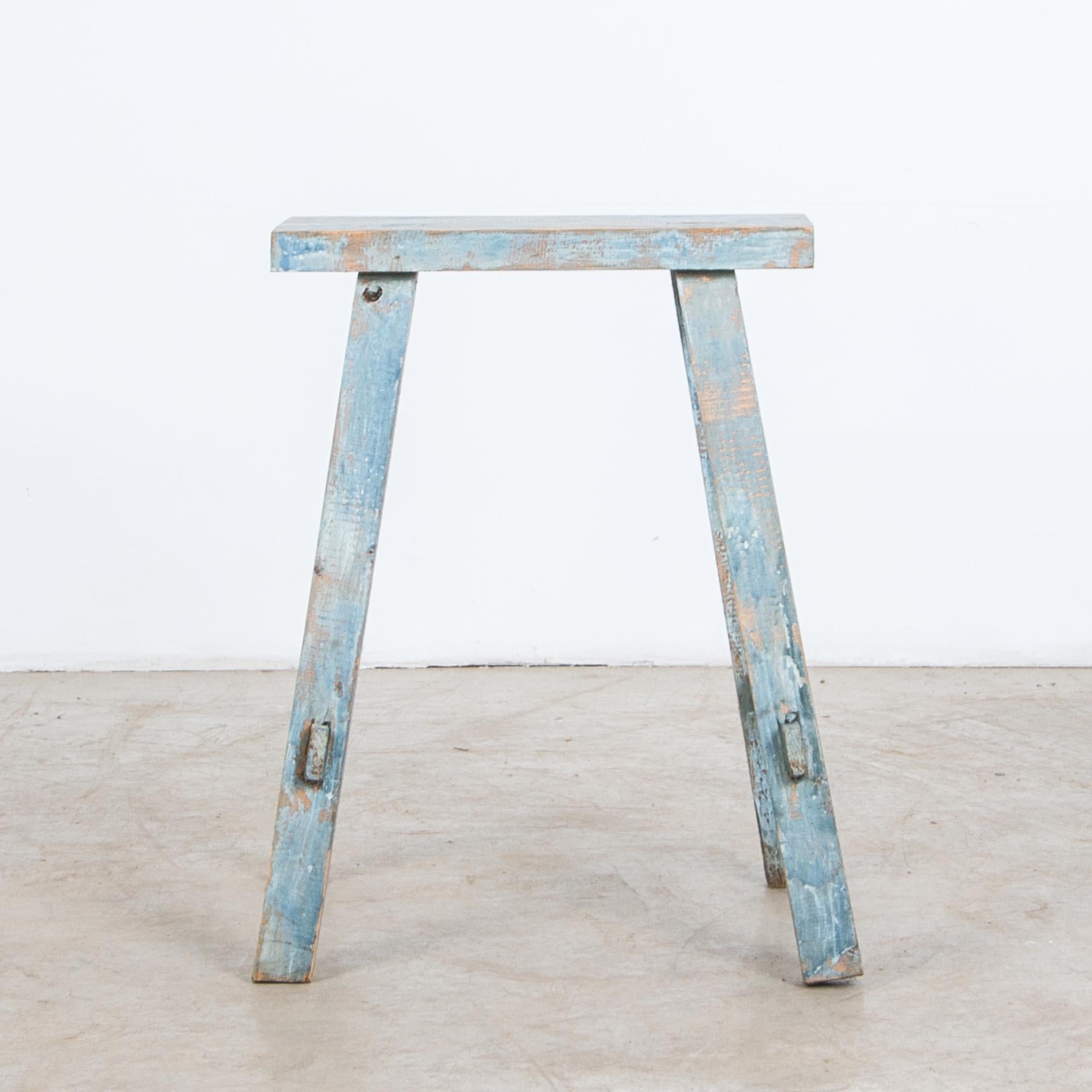 A rustic wooden stool painted in white and blue, a surprising color for this early 20th century wooden farm stool from France. The simplest place to rest your feet, a rustic and sturdy construction makes an understated accent.