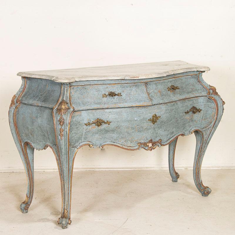 This stunning Venetian Rococo style commode has a remarkable blue painted finish highlighted in gold and burnished red bringing out the carved details. Later professionally painted in blue shades and faux marble white/grey top, the finish has been
