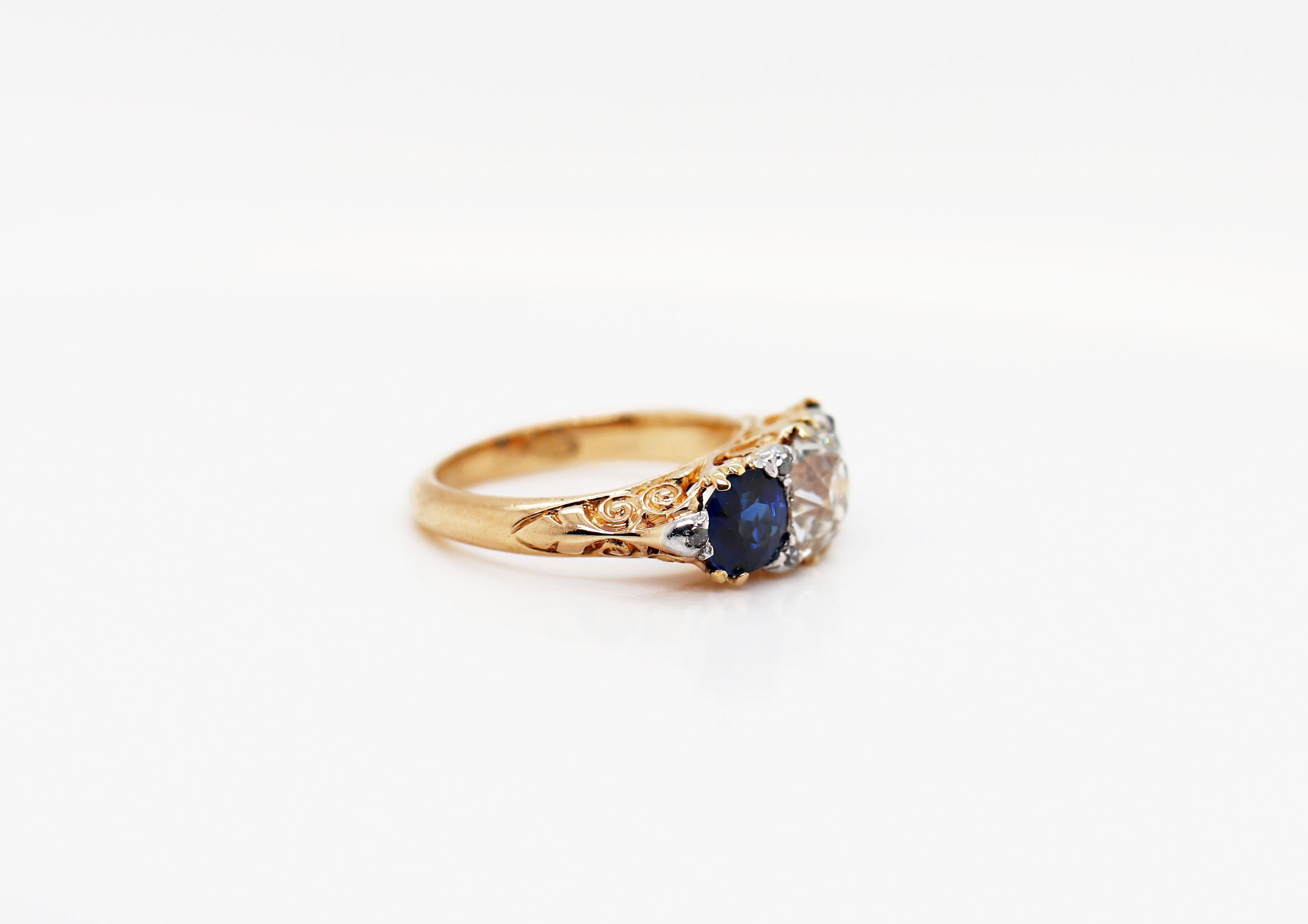 Hand carved Late Victorian three stone ring set with a 1.41ct old cut diamond and two beautiful blue sapphires on either side with a combined weight of 1.61ct all in open back, claw settings. The centre stone is decorated with four old cut diamonds