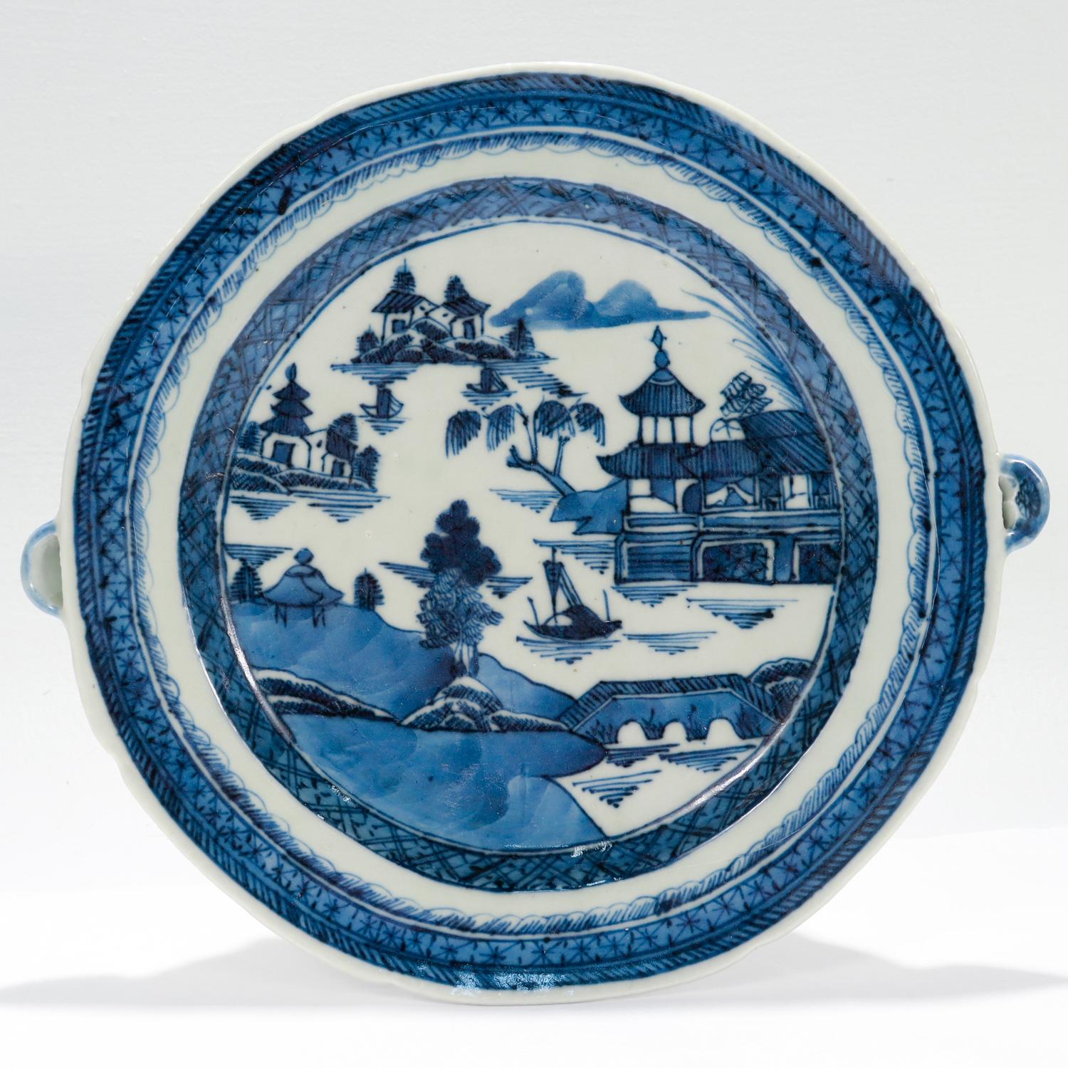 A fine antique Chinese export porcelain warming plate.

In the Canton pattern.

Decorated in underglaze blue depicting a mountainous Chinese village to the top of the lid and the long sides of the body. The background has houses, mountains, and a