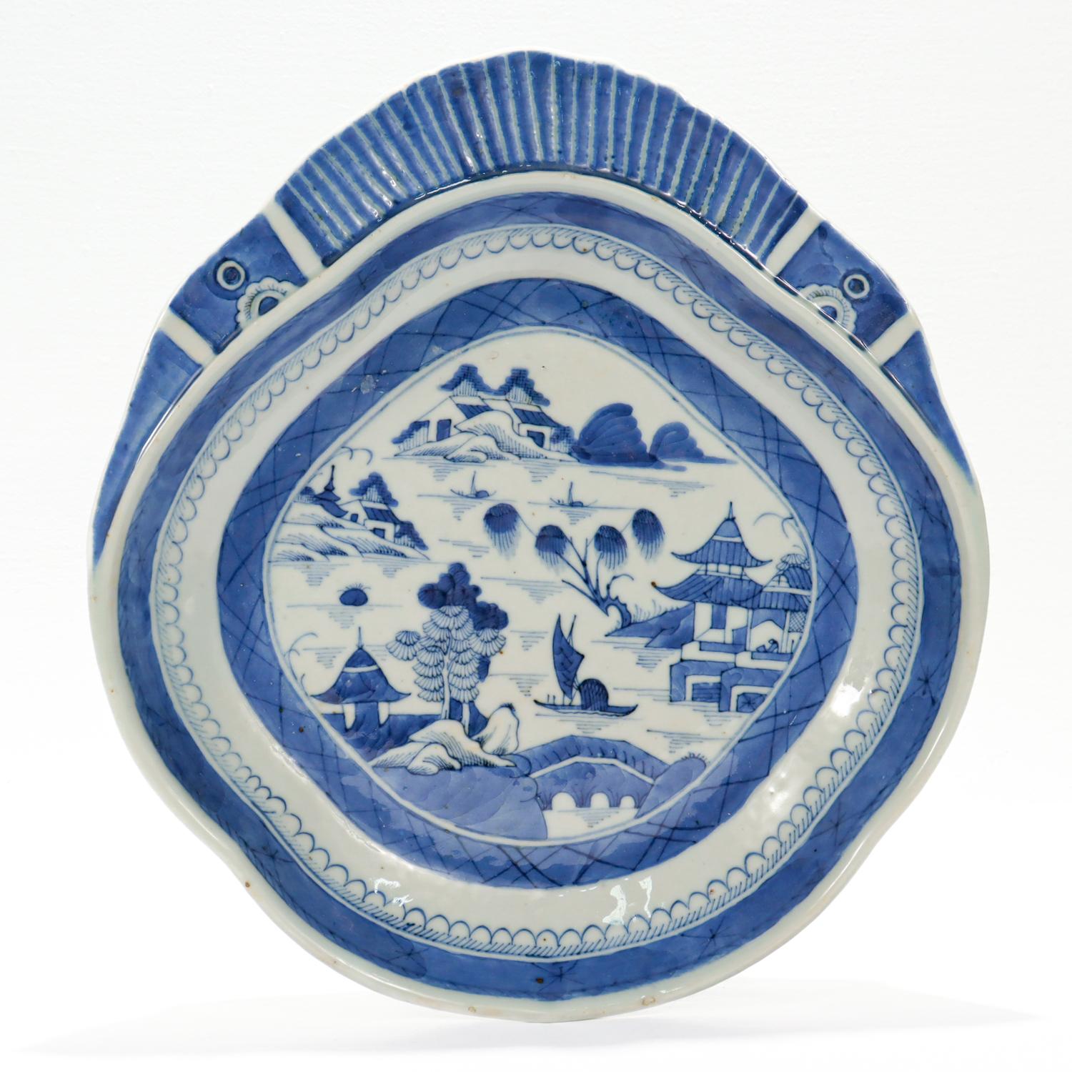 A fine antique Chinese export porcelain shrimp bowl.

In the Canton pattern.

Decorated in underglaze blue depicting a mountainous Chinese village. The background has houses, mountains, and a pagoda. The midground is a river with boats and more