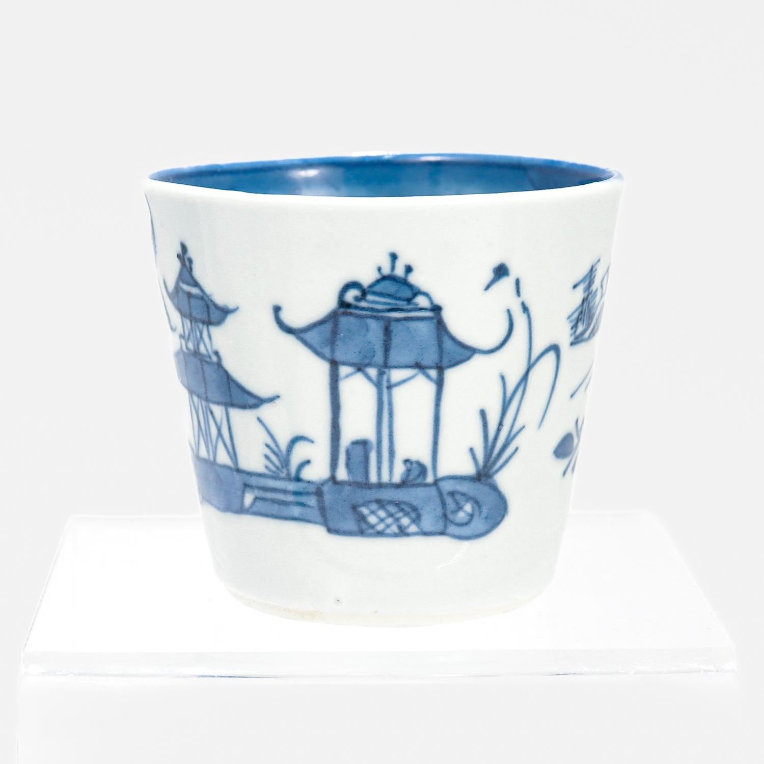 A fine Chinese export porcelain wine cup.

In the Canton pattern. 

With a white ground decorated in underglaze blue.

The exterior of the cup depicts Chinese buildings and plants. 

The interior of the cup with a floral spray to the center and a