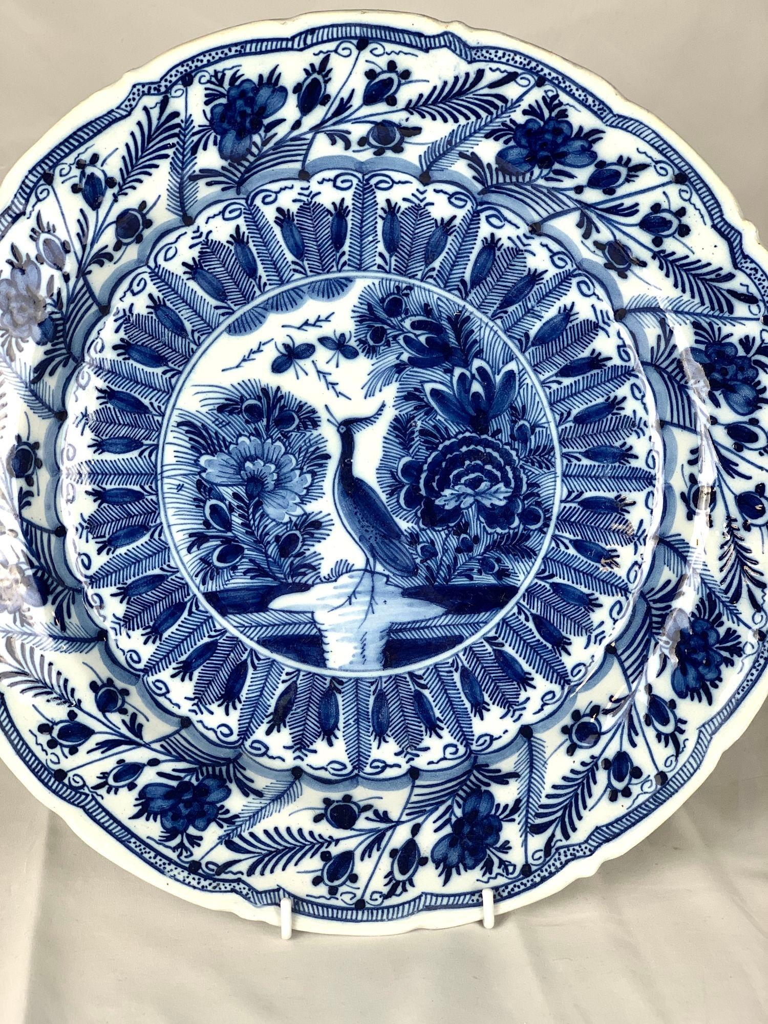 Cet exceptionnel plateau bleu et blanc de Delft a été fabriqué par la manufacture De Klaauw (La Griffe) vers 1780.
Toute la surface est richement décorée en bleu cobalt vibrant.
Le centre représente un paon debout dans l'eau, entouré de fleurs