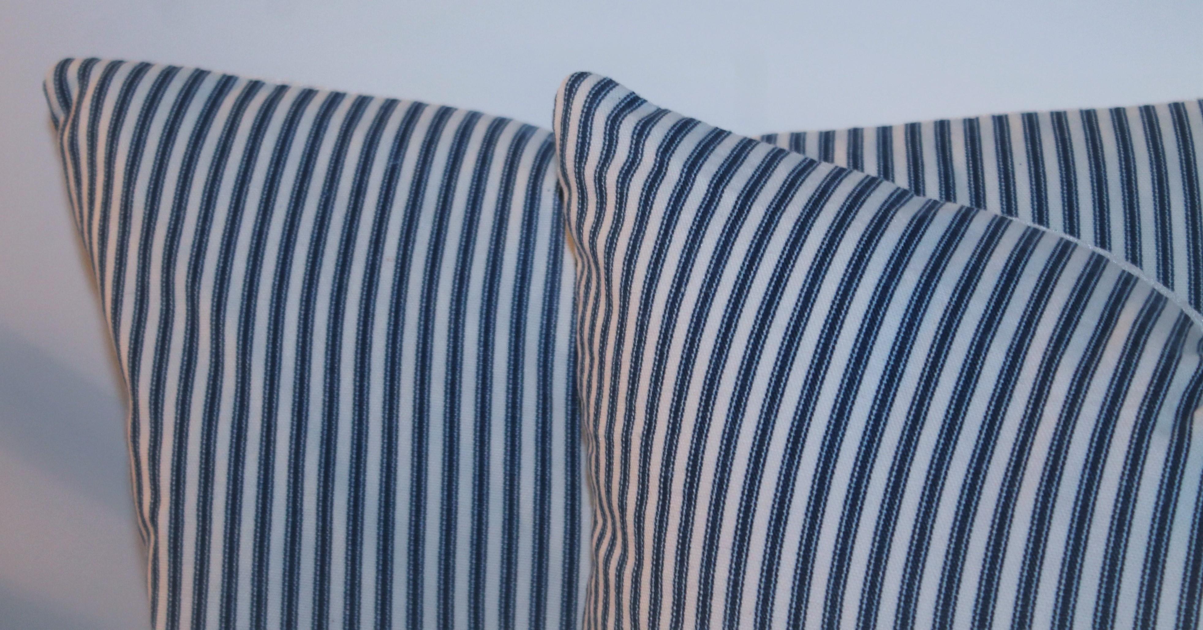 Antique ticking pillows with white linen backings. The inserts are down & feather fill. The collection of four pillows, two pairs.