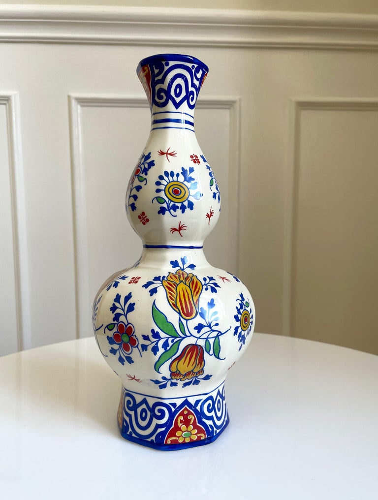 Colorful 100 year old Belgian delft faience knobble vase by Charles Catteau's Boch Fréres Keramis at La Louviére, Belgium in the 1920s. hand painted flowers, leaves and organic patterns in vibrant blue, red, yellow and green colors on cream white