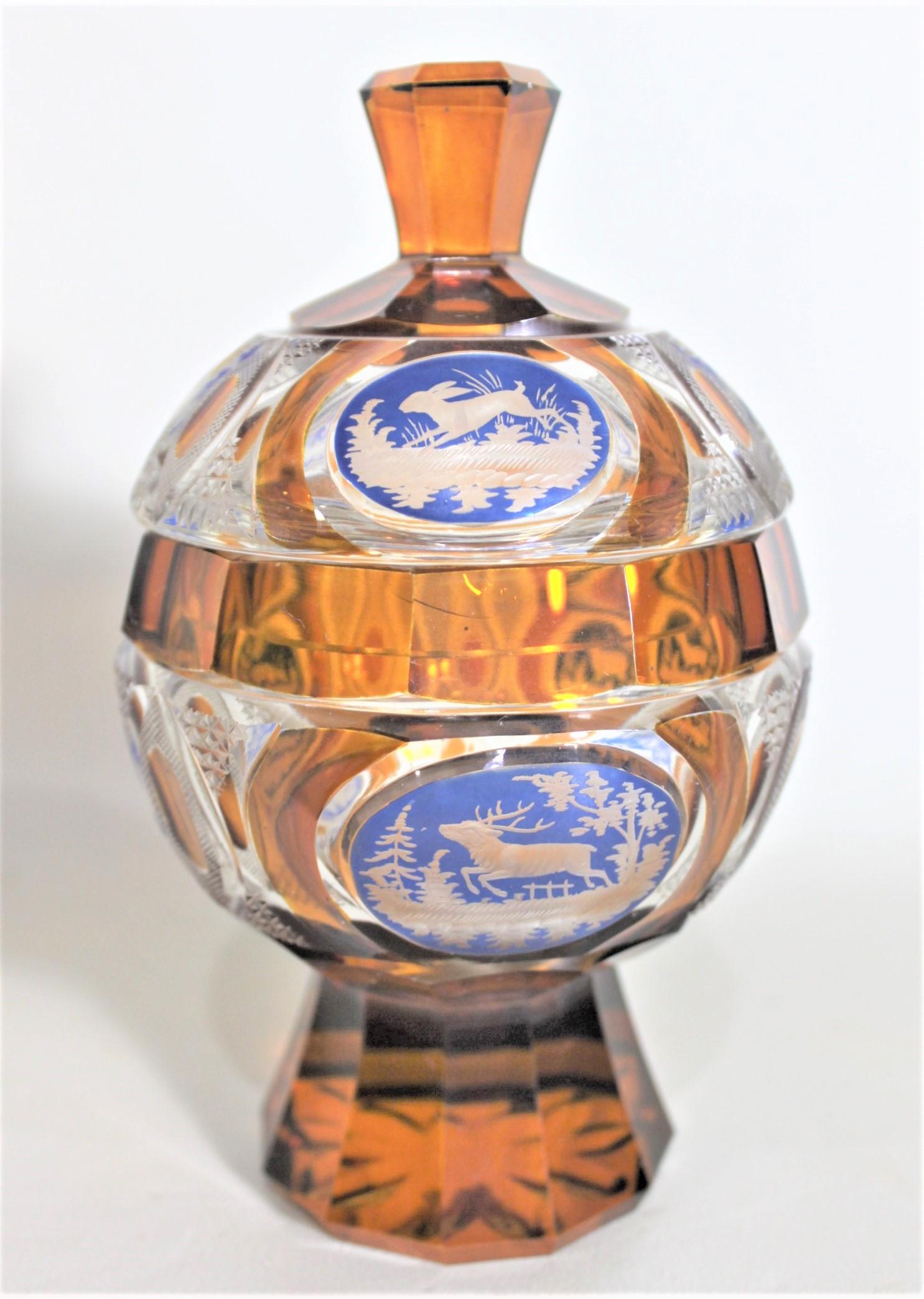 This cut crystal covered goblet styled compote is unsigned, but presumed to have been made in the region of Bohemia, likely the Czech Republic in approximately 1920. The compote features the use of amber and blue glass which has been very nicely