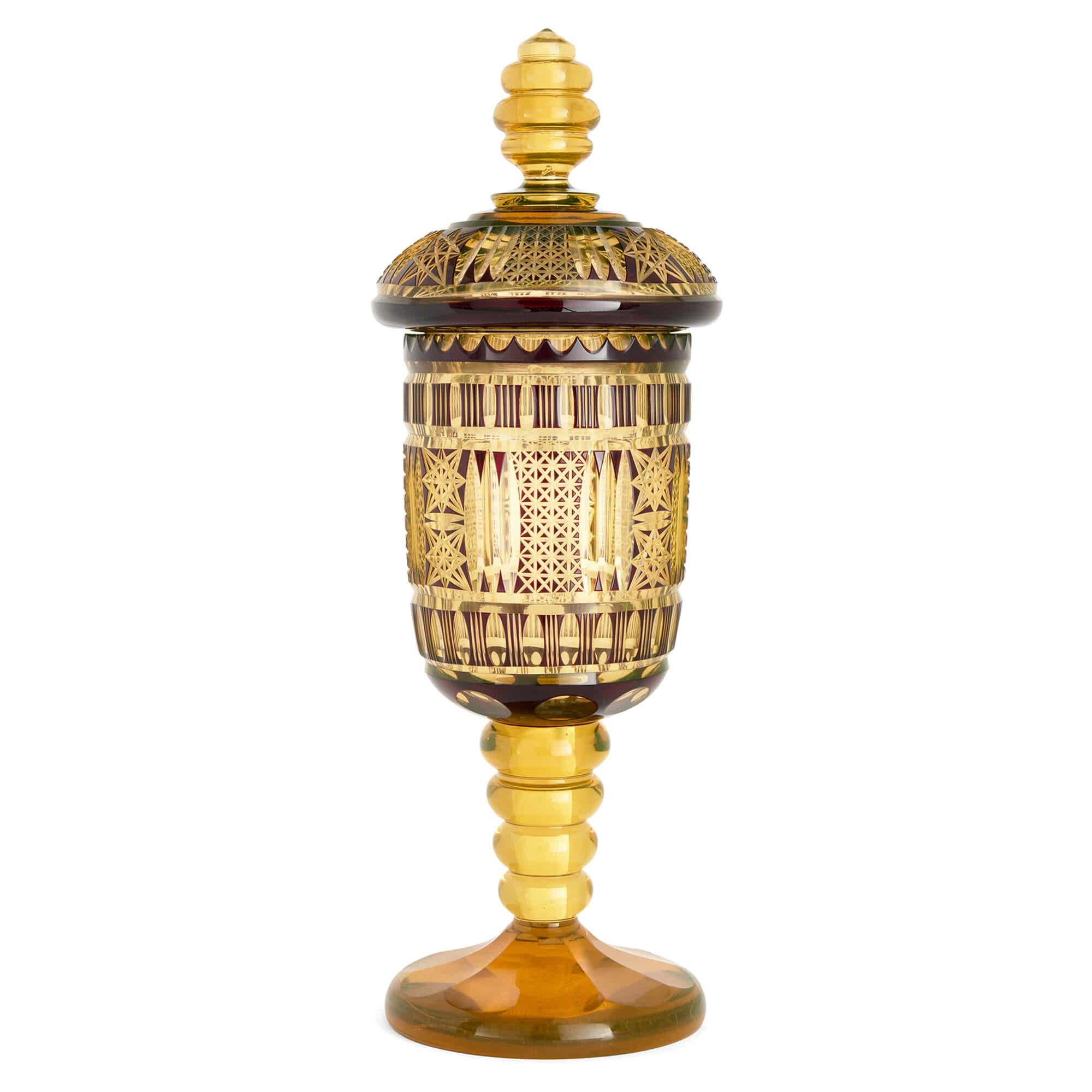 Antico calice e coperchio in vetro ambrato di Boemia 
Boemia, Fine del XIX secolo 
Altezza 37 cm, diametro 13 cm

Questo squisito calice boemo, noto anche come pokal, risale alla fine del XIX secolo ed è un esempio magistrale di arte vetraria