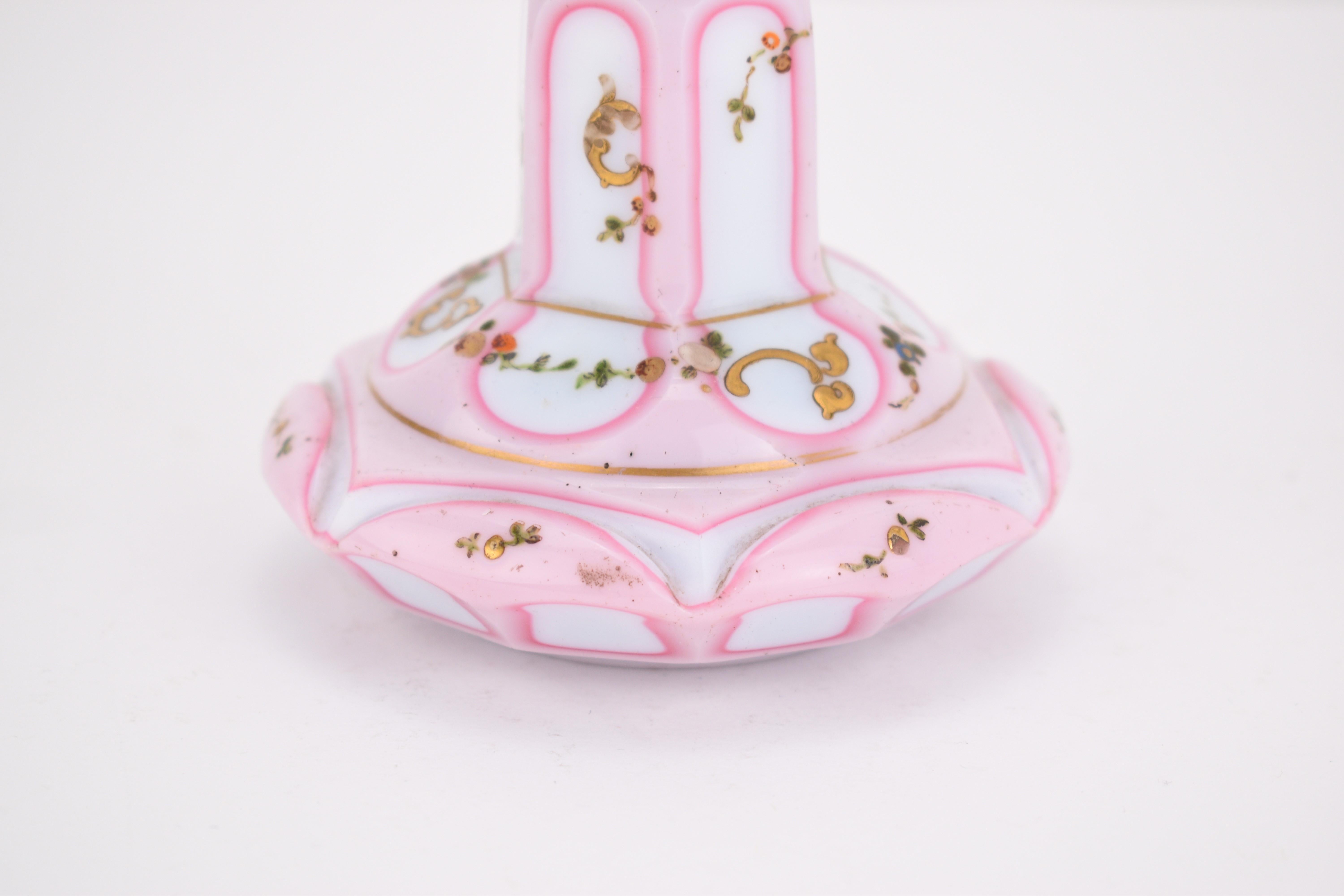 An exquisite example of 19th-century Bohemian craftsmanship, this double overlay perfume bottle features milky white and rose pink opaline glass.

The body is cut into six side panels, each bordered by the delicate glass overlay and hand-painted