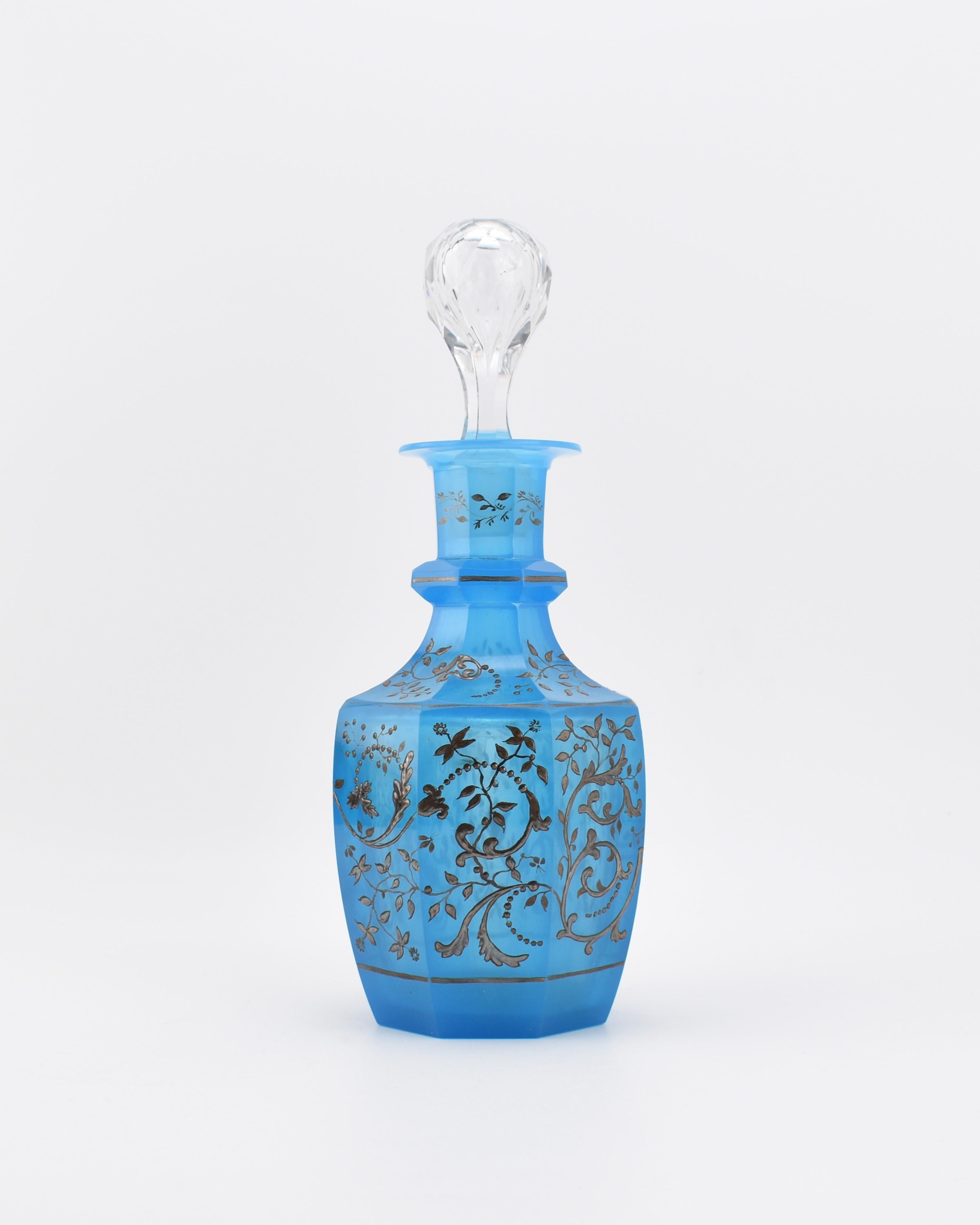Très rare carafe à décanter Biedermeier avec bouchon en verre opalin bleu albâtre.

Le corps a été découpé en 8 panneaux latéraux avec une décoration continue en argent peinte à la main tout autour du cou et du corps, présentant diverses formes de