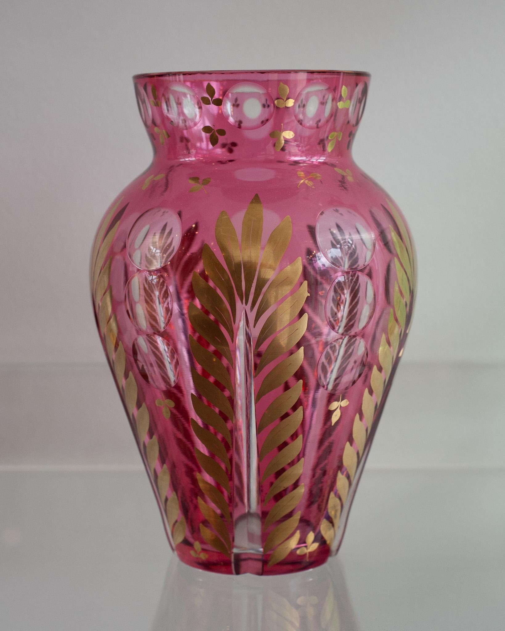 A beautiful antique bohemian cranberry glass vase with clear cut details and gold gilded leaf detail.