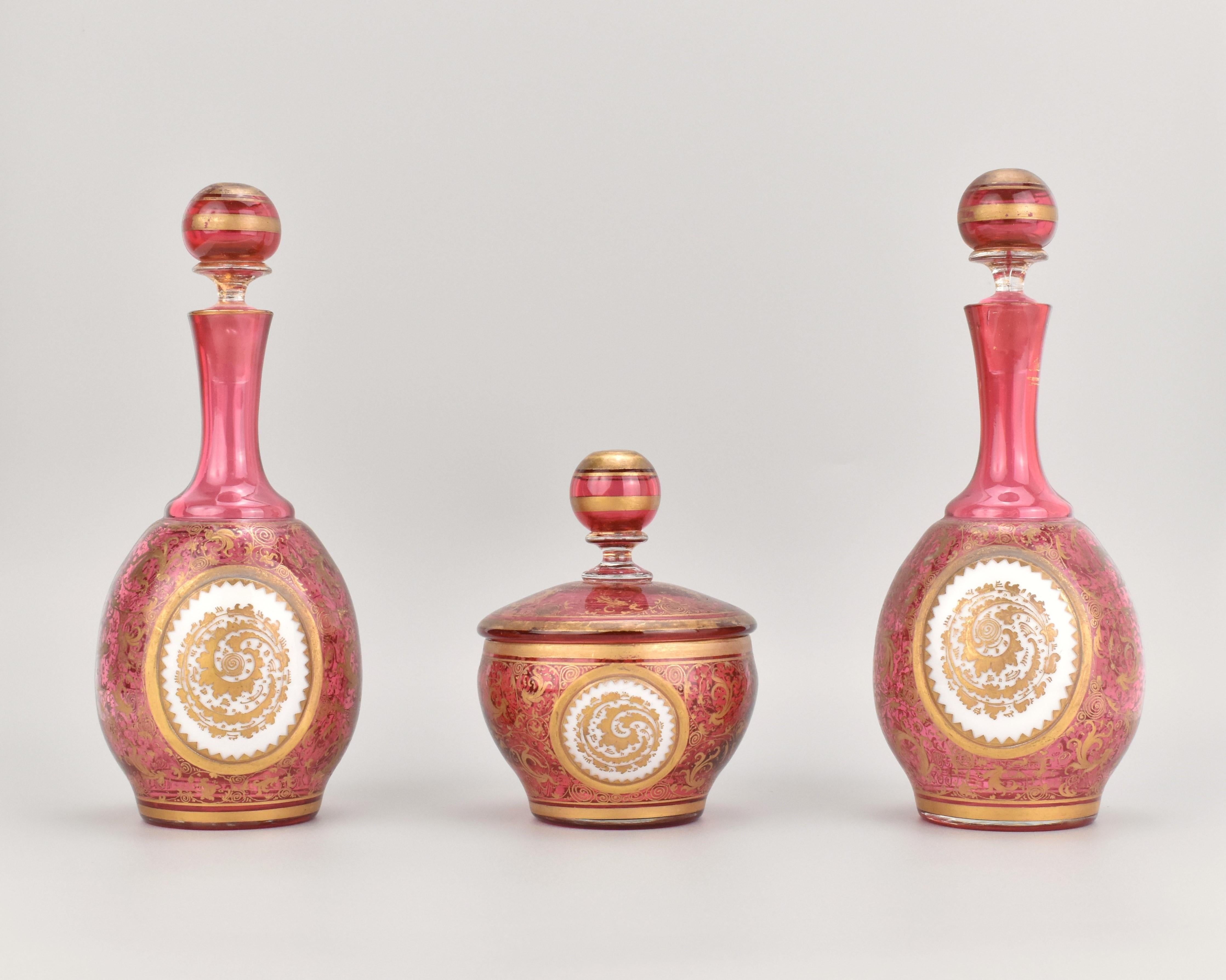 Satz von zwei Preiselbeer-Glasflaschen mit Stopfen und Schale mit Deckel - Moser, Bohemia, 1860

Dieses elegante Set aus zwei Flaschen mit Stopfen und einer passenden Schale mit Deckel ist aus Preiselbeerglas mit einem auffälligen weißen