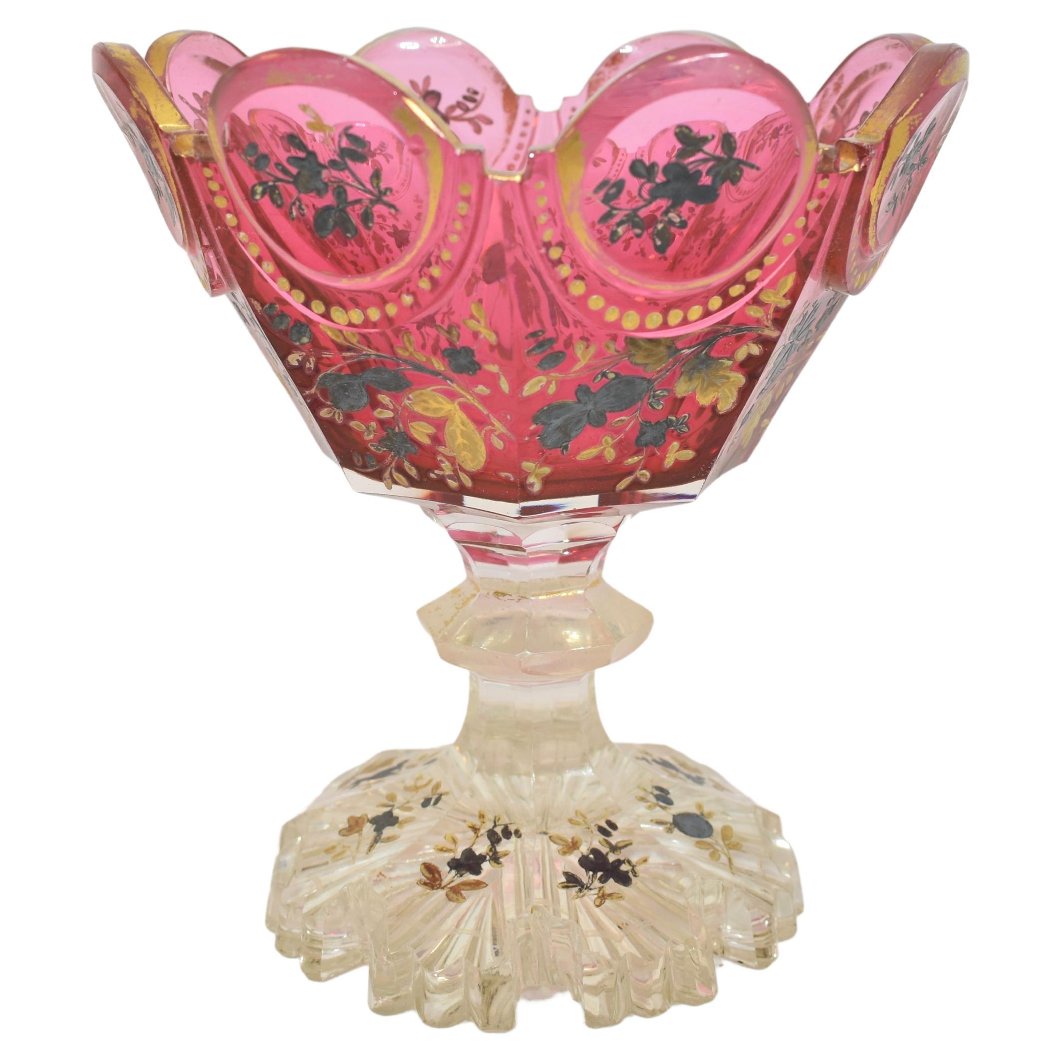 Antike Tazza-Schale aus cranberryfarbenem Glas
steht auf einem geschliffenen Klarglas-Fuß mit ausgestellter Basis am Boden
rundum mit Gold- und Silberemaille verziert
schönes Beispiel für das hochwertige böhmische Glas des 19. Jahrhunderts.