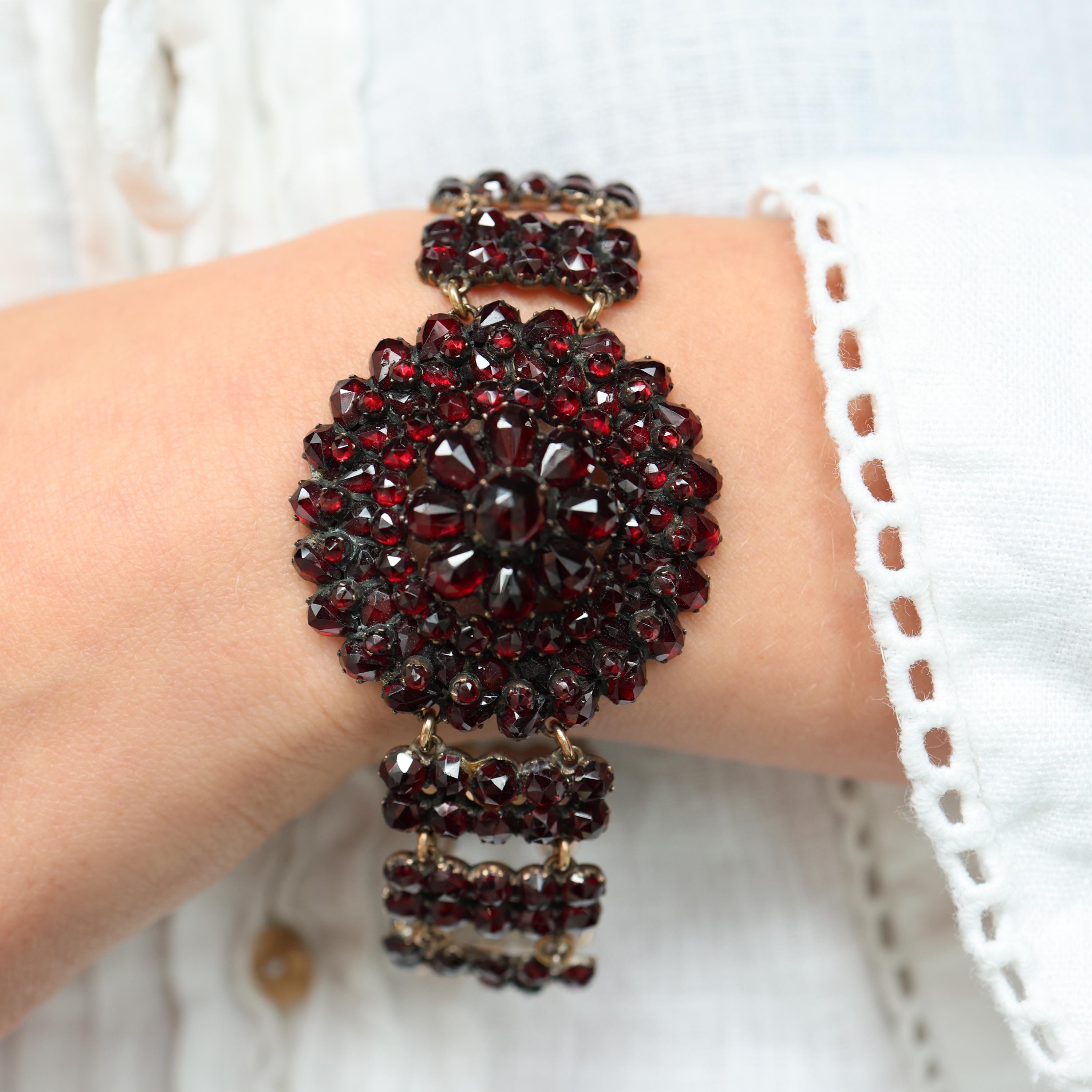 Bracciale di granati di Boemia, composto da granati tagliati a rosa, con un gruppo centrale circolare di granati di dimensioni graduali; il bracciale è composto da barre verticali, ciascuna con due colonne di granati, collegate tra loro da anelli a