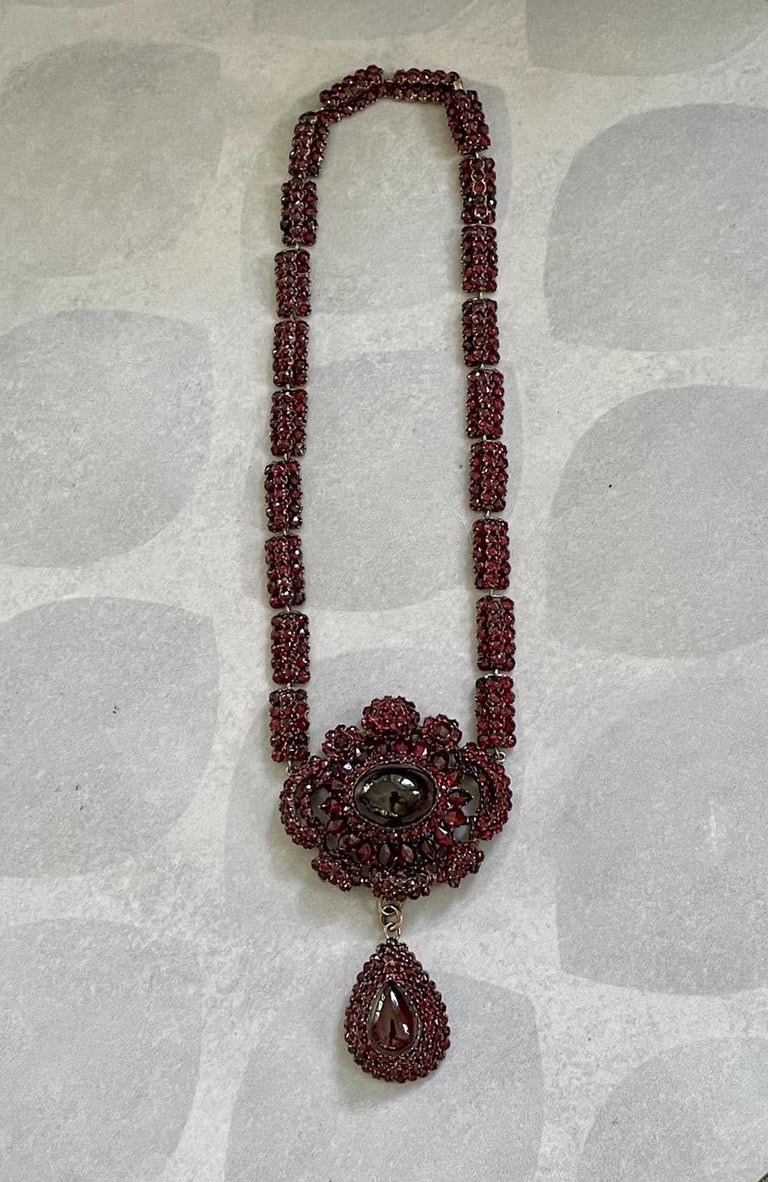 This fabulous antique Bohemian Garnet Silver Gilt choker necklace features a two large cabochon Garnet stones in the pendant; one oval-shaped and one is teardrop-shaped. Smaller stones circle the wearer's neck in links, each with three rows of five