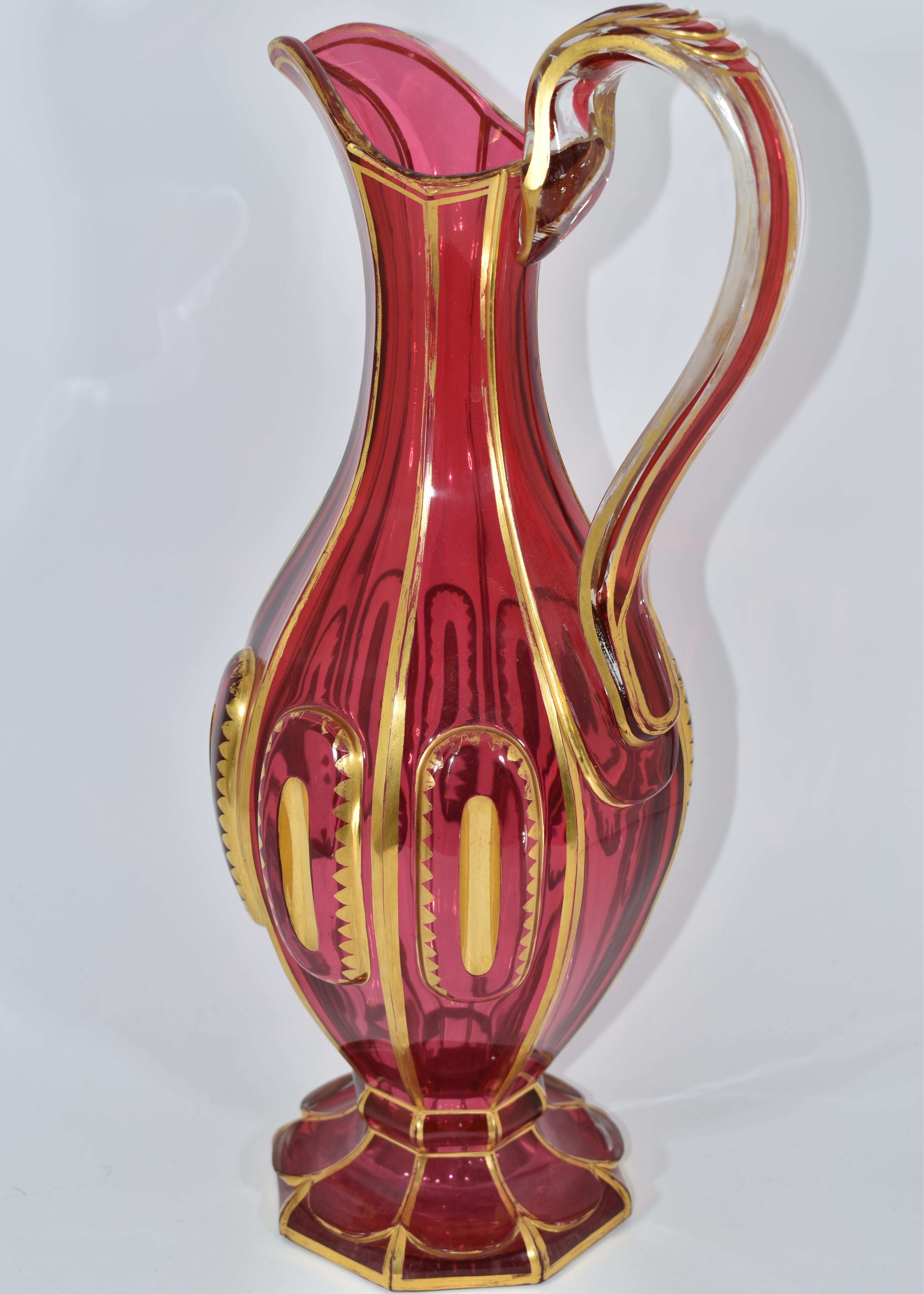 Large antique cranberry glass pitcher.
Bohemian, 19th Century
The circular body is cut in 8 side panels with decorations and gilding all around.
Height (35 cm)
Diameter (15 cm).
