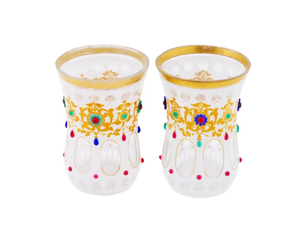 A pair of antique late 19th-century Bohemian frosted glass cups. Curved shape. Cut to clear decorative elements, gilt hand-painted ornaments, overlay glass cabochons in red, green, and blue. Collectible Glassware, Tableware And Serveware.

OVERALL