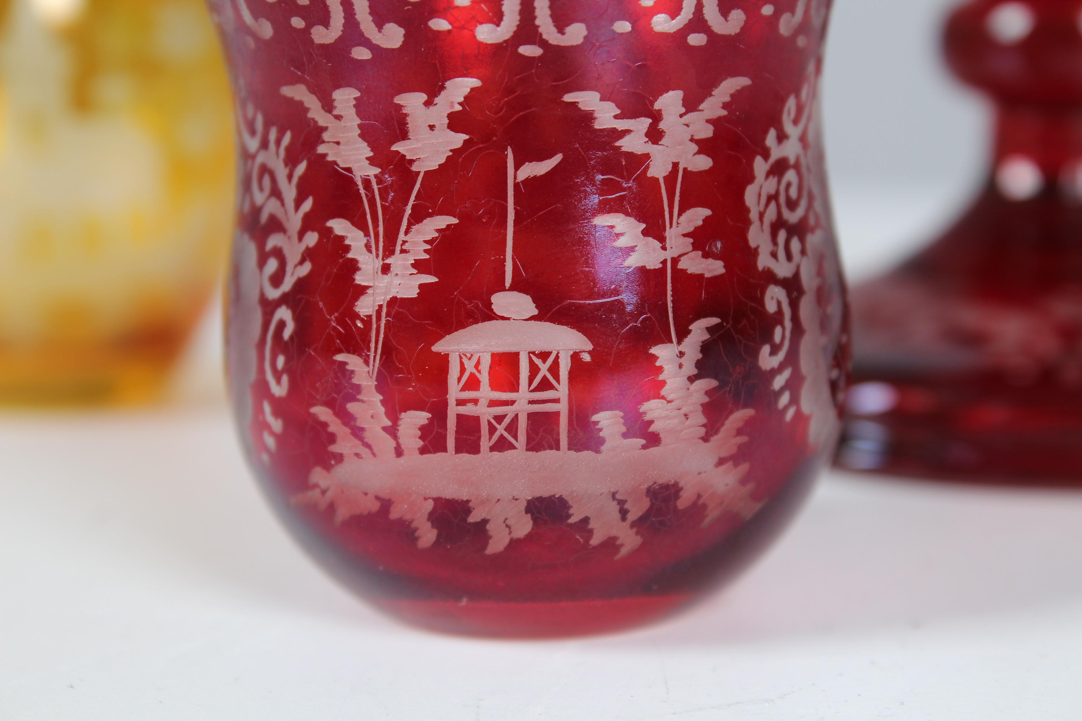 Beautiful glass set made of Bohemian glass. The set consists of a large ruby serving bowl, a small ruby glass and a small sunny yellow vase. The fine crystal carving depicts, among other things, a hunting scene and various houses and floral