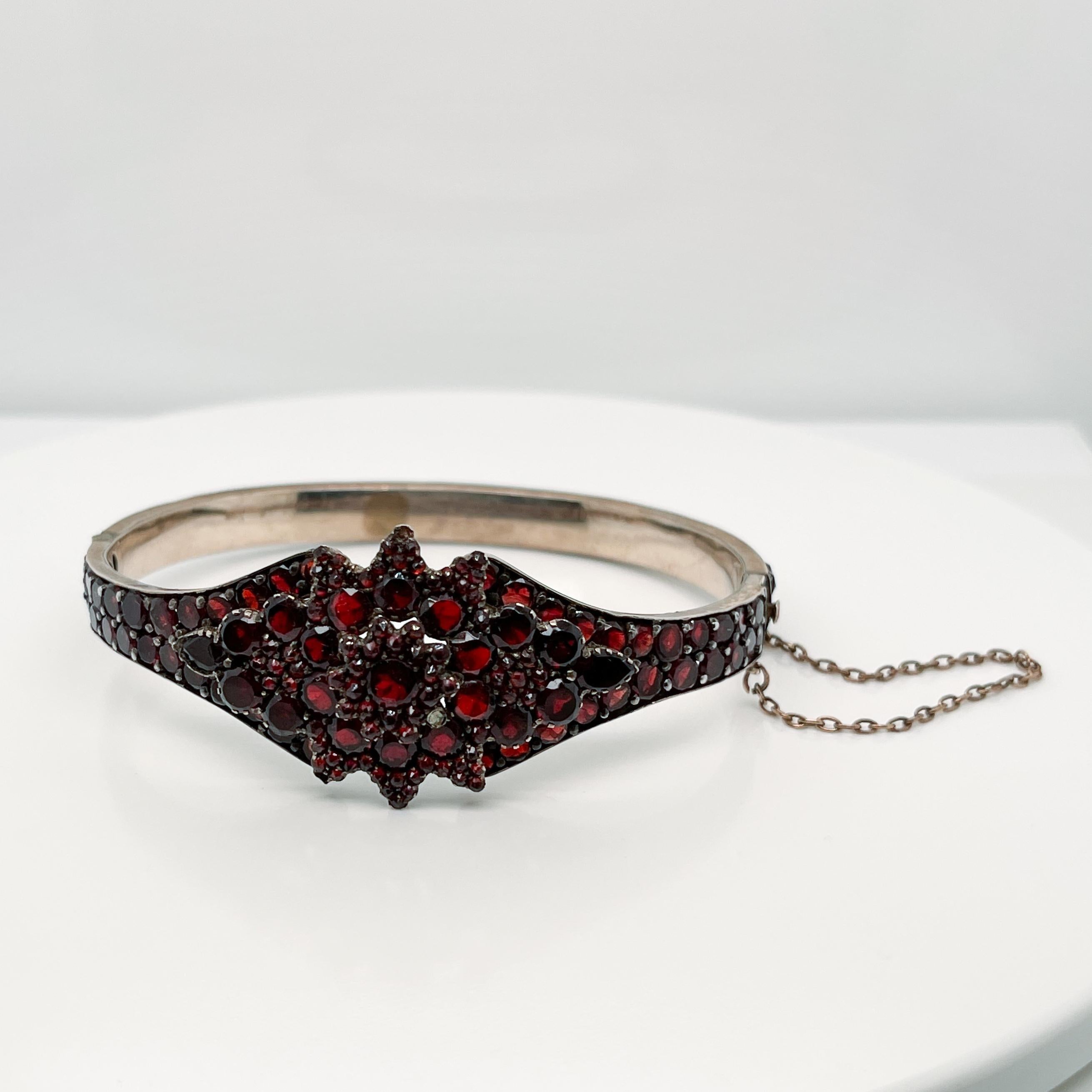A very fine Antique Bohemian gold-filled bangle bracelet. 

Prong set with garnets in a flower pattern to the top and around the circumference of the bracelet. 

The bracelet opens at the middle on a hinge and is secured by both a box clasp and