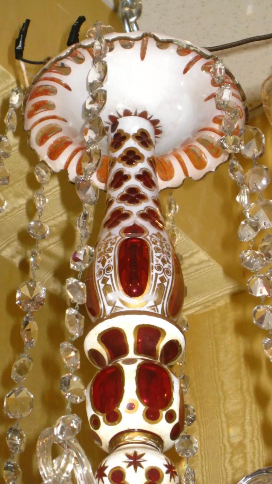 Bohemian glass chandelier made for the Middle Eastern market with six electrified candle arms with clear glass hurricane shades with gilt decorations, and a center stem with cased glass sections of white glass cut to ruby red and white glass cut to