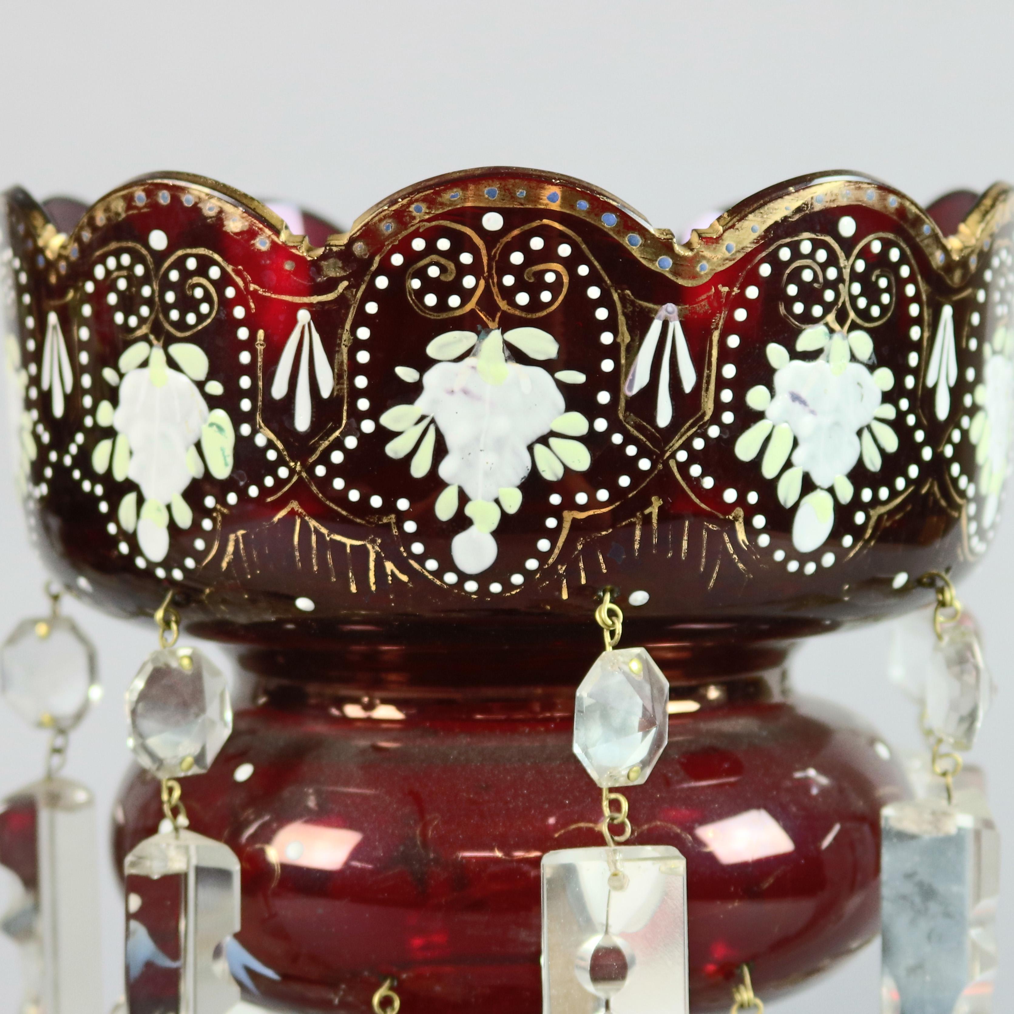 An antique Victorian pair of mantel lusters offer ruby glass construction with ruffled rim bowls having hand painted and gilt floral and scroll decoration and highlighted with cut crystal prism, circa 1880

Measures: 13.5