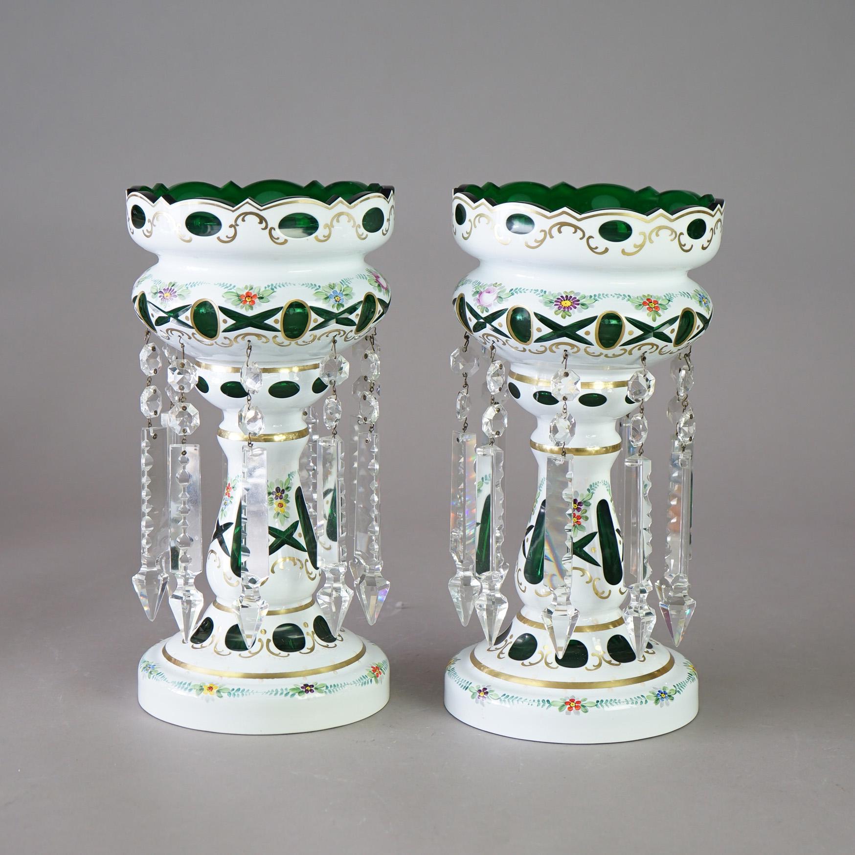A pair of Bohemian mantel lustres offer white painted cut-to-clear emerald green glass construction with hand painted floral decoration, hanging crystal prisms and gilt highlights, 20th C

Measures - 13