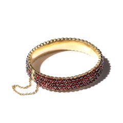 Antiguo brazalete de bisagra bohemio con incrustaciones de granates en montura de oro granate