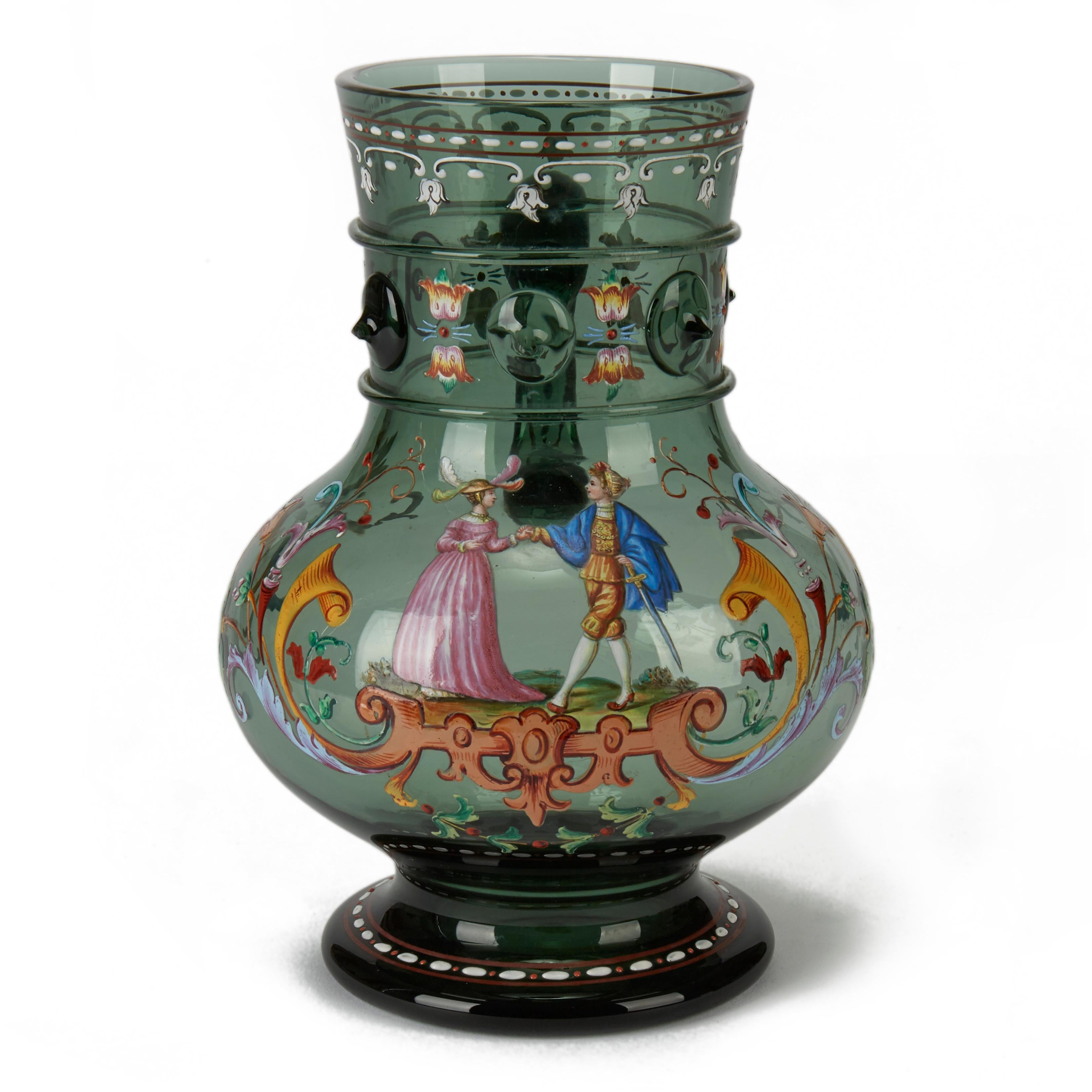An exceptional antique bohemian green glass beer stein, attributed to Moser with a courting couple set amidst scroll and floral designs with finely applied detail and bright and colorful enameling. The stein has prunts and collars applied around the