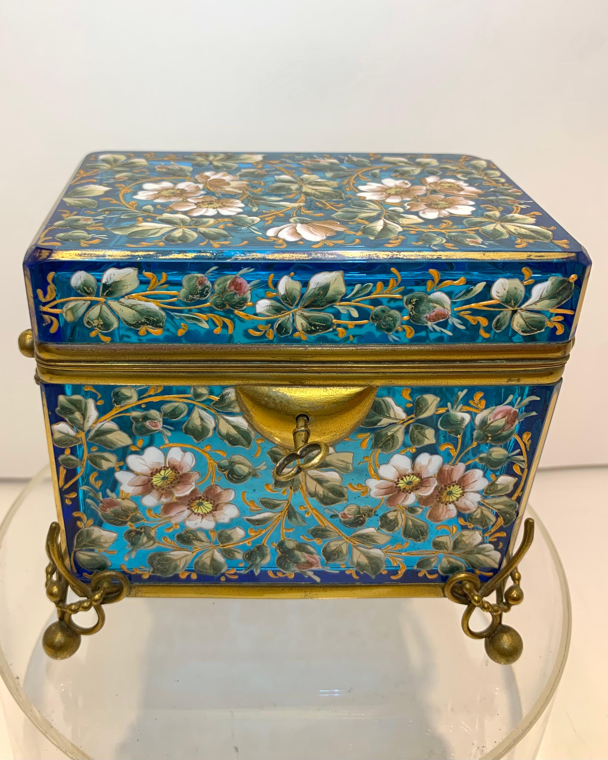 Fine Moser Casket Jewelry Box with Hinged Bronze Mounts

Standing on Dore Bronze Feet and Matching Swinging Handles

Lid and Base are Both Framed in Bronze

Generously Enameled all Around with Colorful Sprigs, Flowers and Leaves

Original
