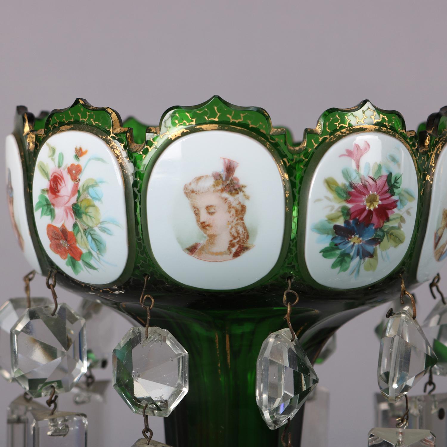 Antique Bohemian Moser School mantel lusters feature emerald green glass construction with scalloped bowls having hand painted panels of portraits and floral spray decorated with hanging cut crystals and raised on faceted and flared column supported