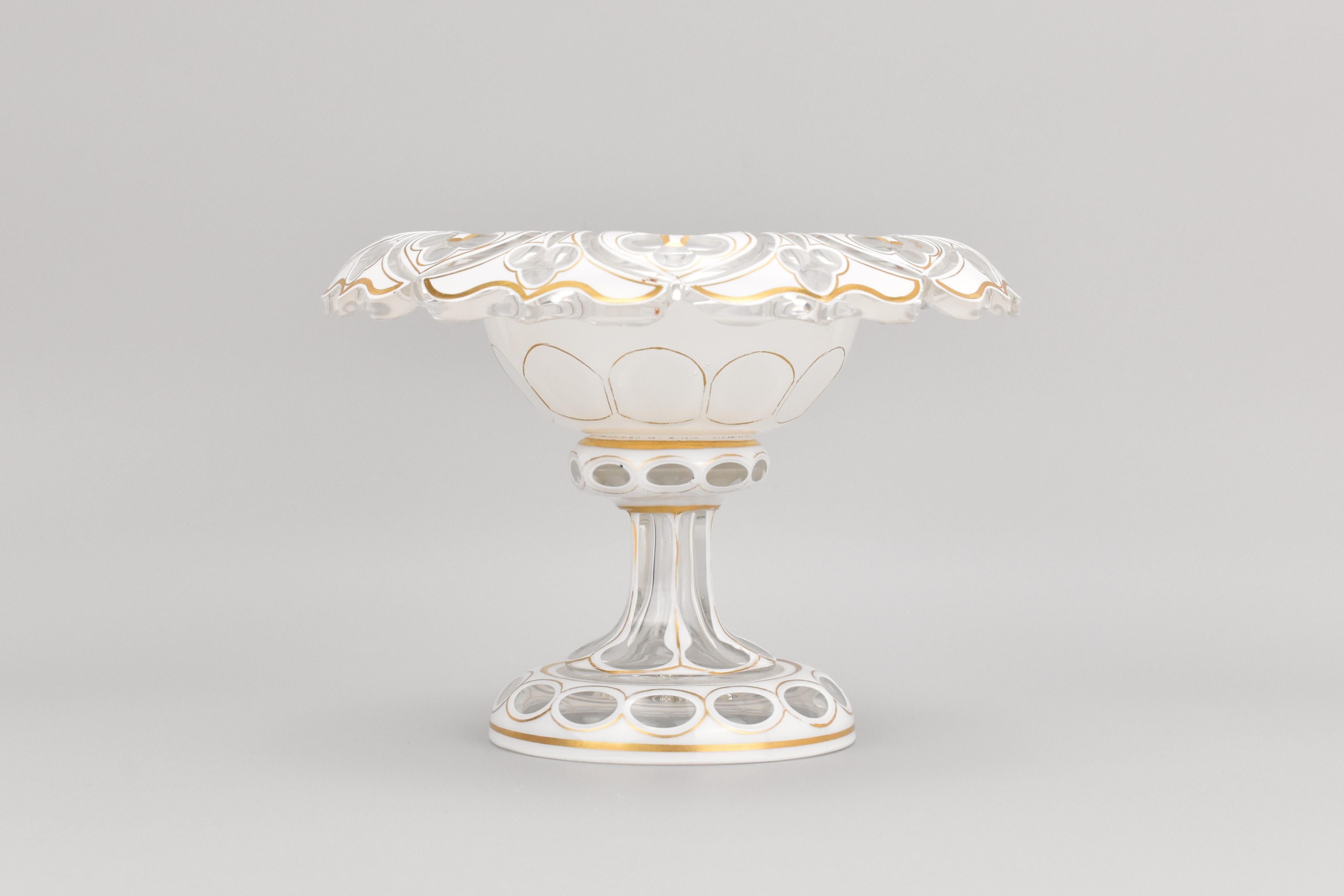 Este antiguo centro de mesa en forma de cuenco para caramelos, fabricado en vidrio superpuesto en la Bohemia del siglo XIX, es una asombrosa representación de la célebre tradición vidriera de la región. El cuenco presenta un diseño de doble capa,